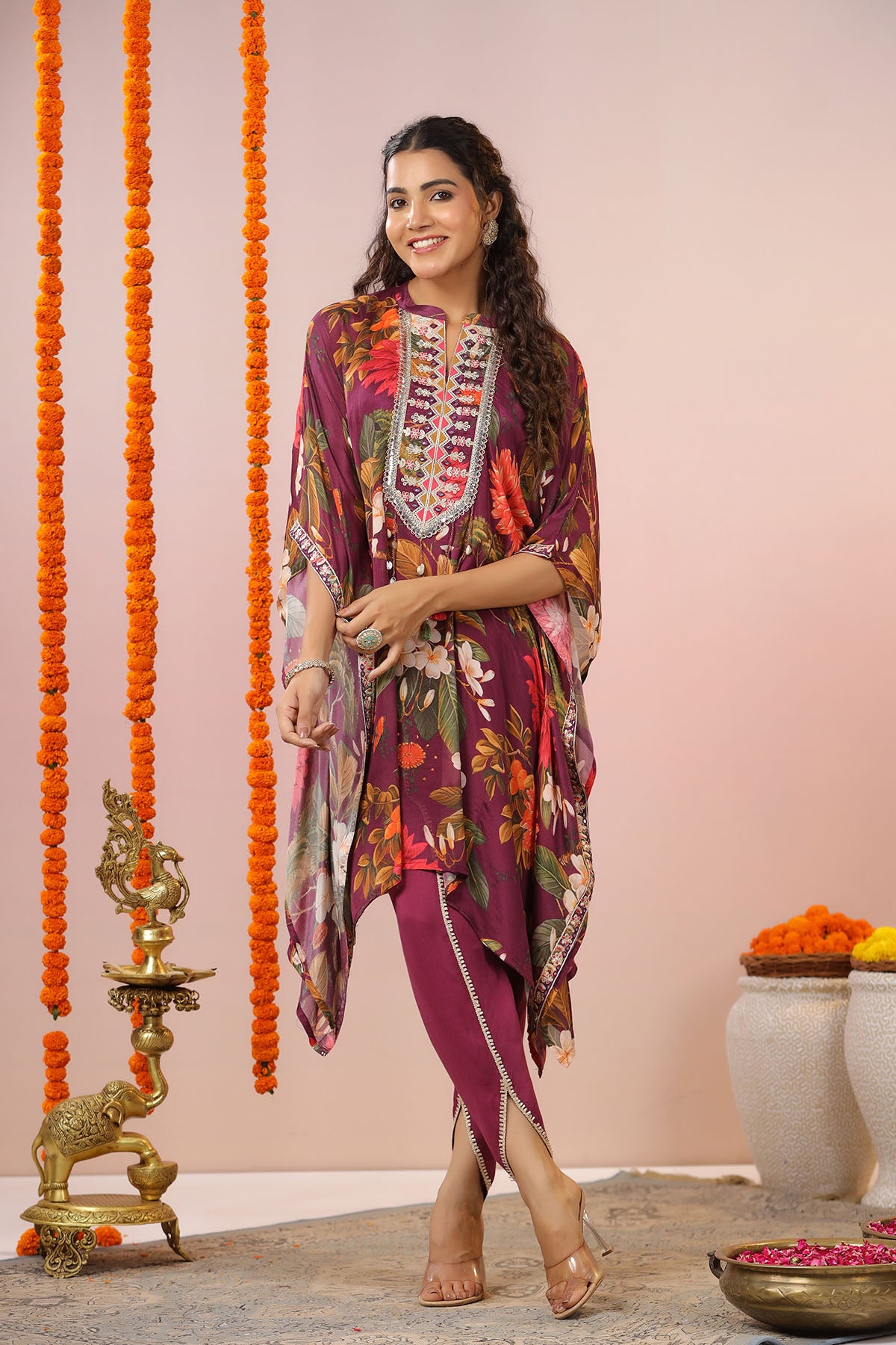 Woman in a colorful traditional outfit standing in front of decorative elements.