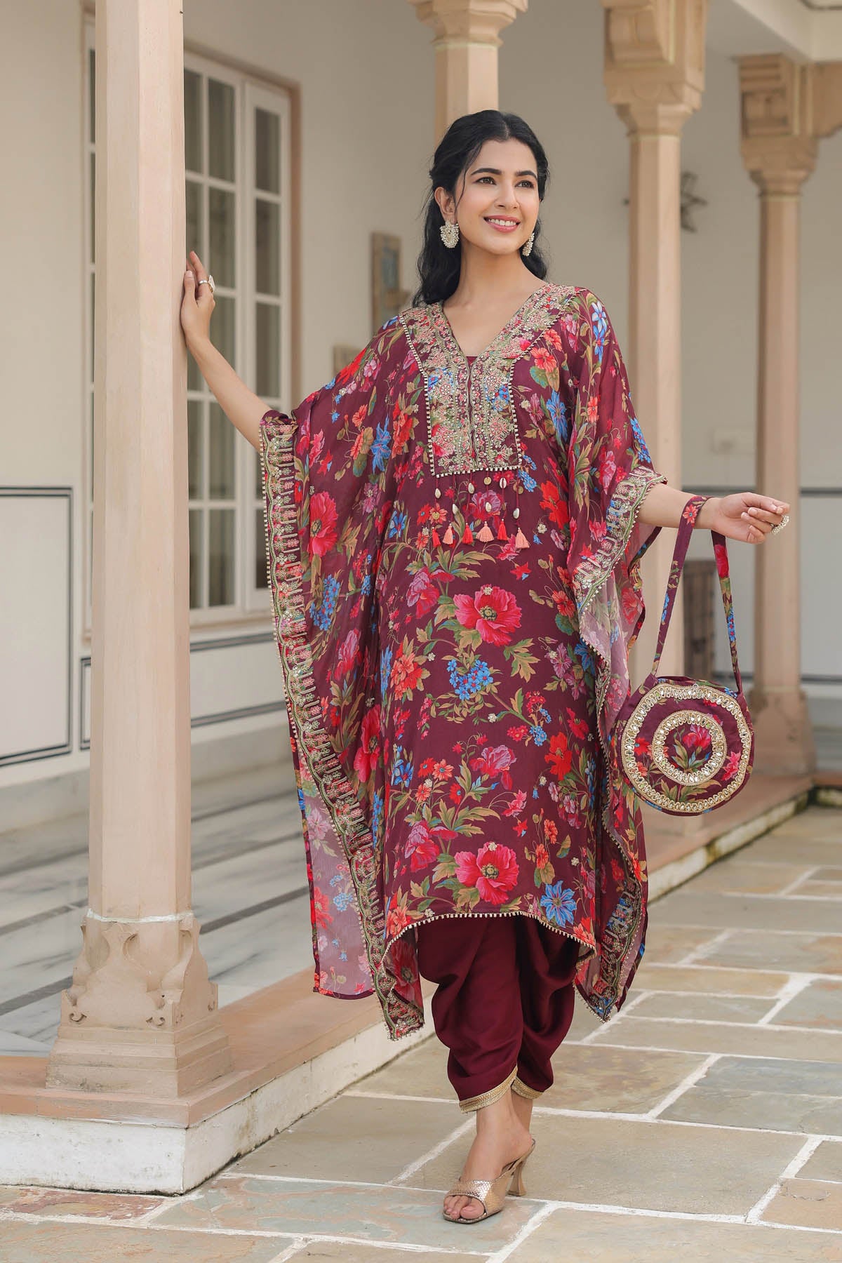 Woman in a colorful floral outfit standing in an elegant interior setting.