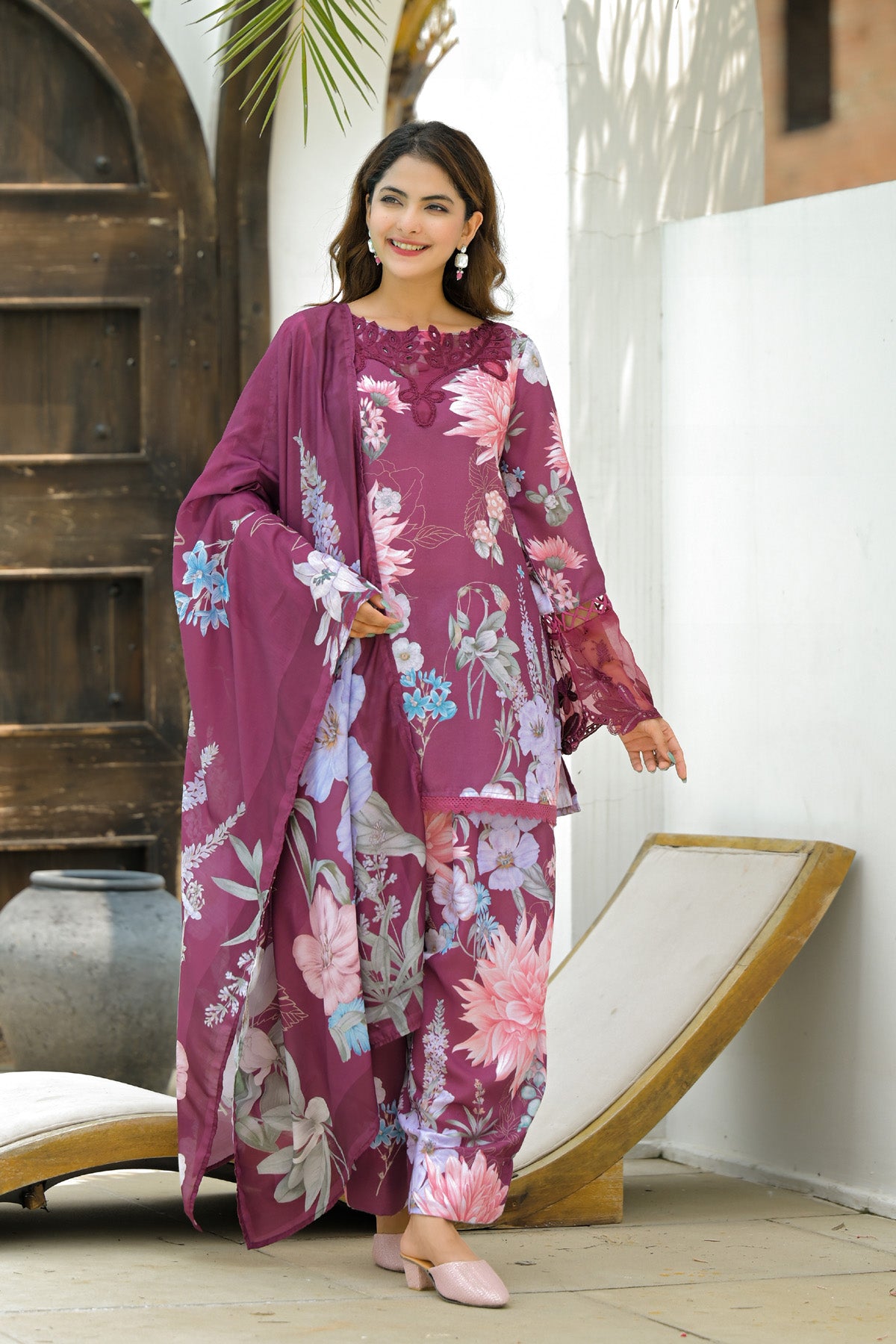 Woman wearing a floral dress with a matching dupatta in an outdoor setting.