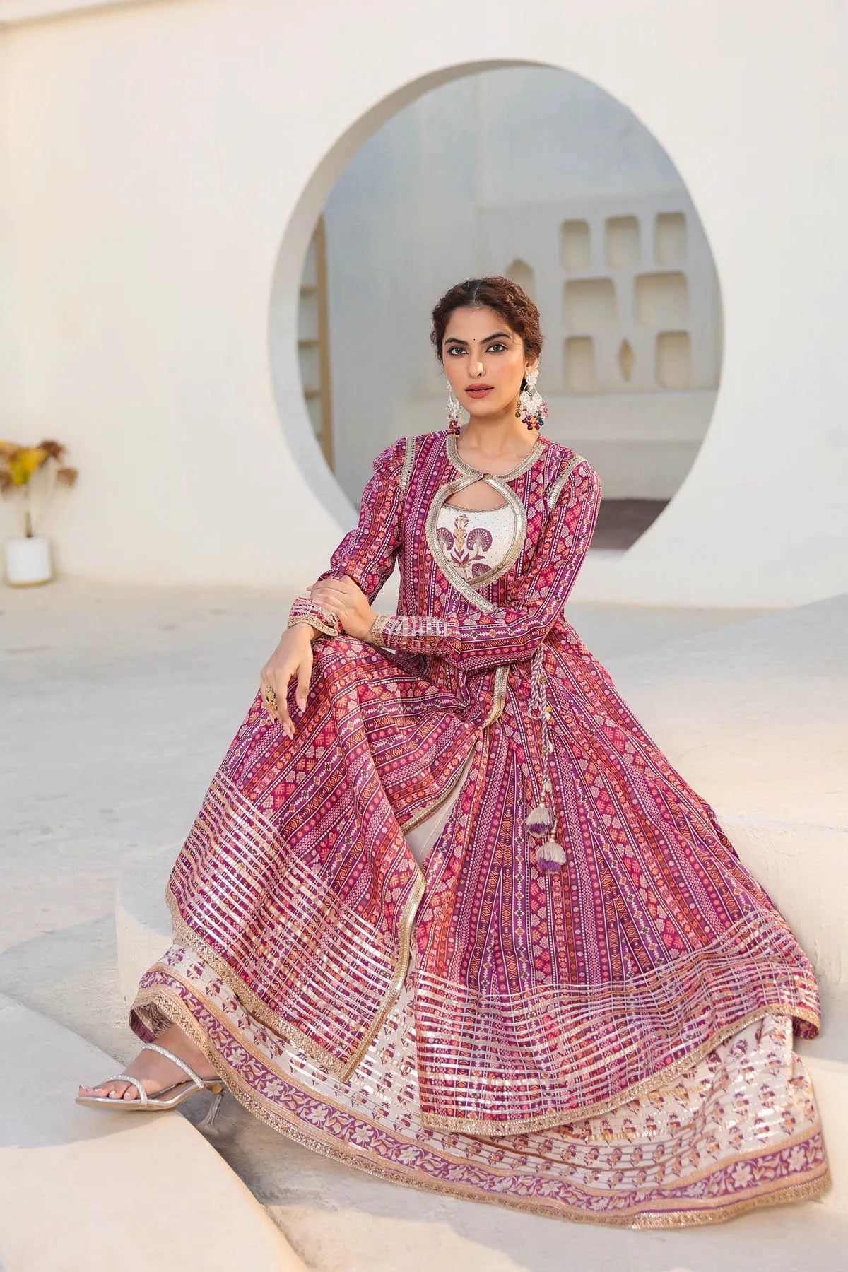 Woman in a traditional pink and white embroidered outfit sitting on a white staircase.