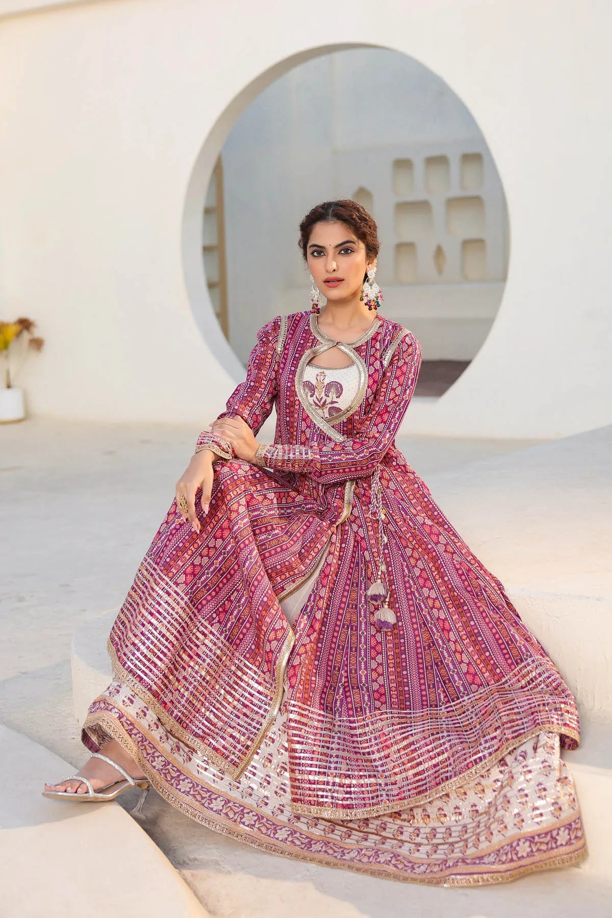 Woman in a traditional pink and white outfit sitting on a white staircase.