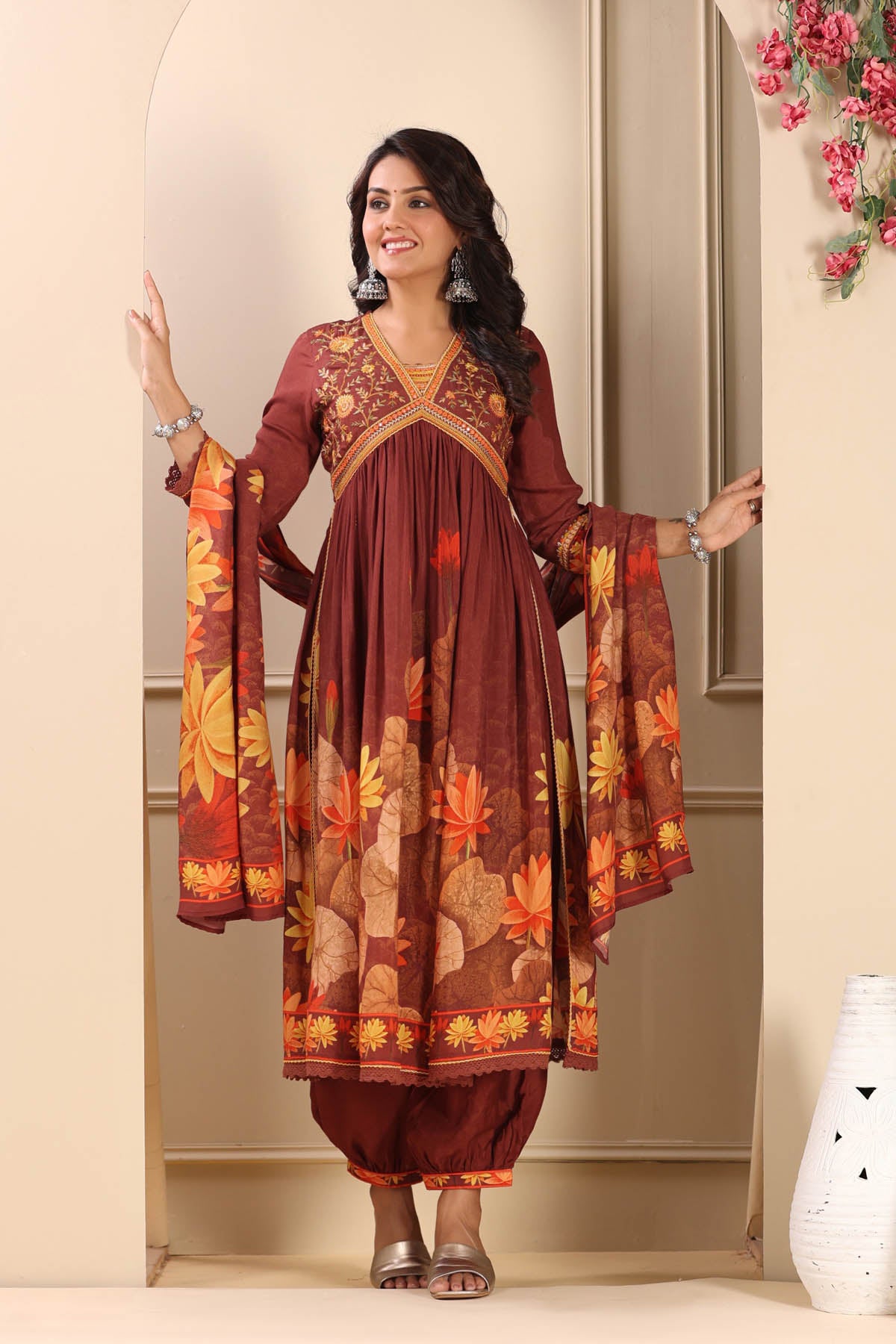 Woman wearing a traditional outfit with floral patterns in a home setting.