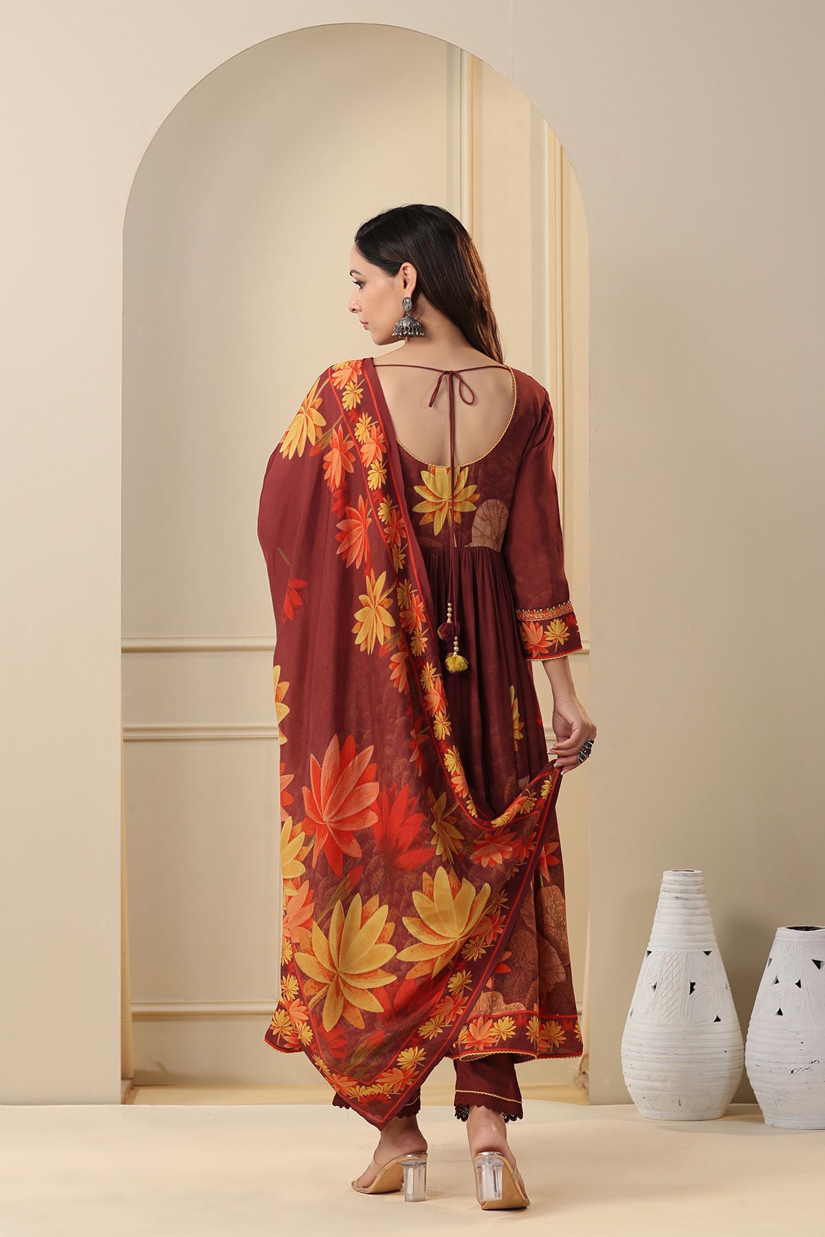 Woman wearing a floral dress with a backless design, standing in front of a mirror.