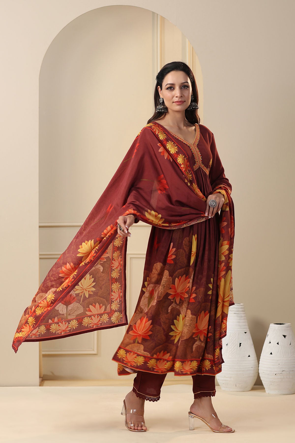 Woman wearing a traditional outfit with floral patterns in a neutral setting