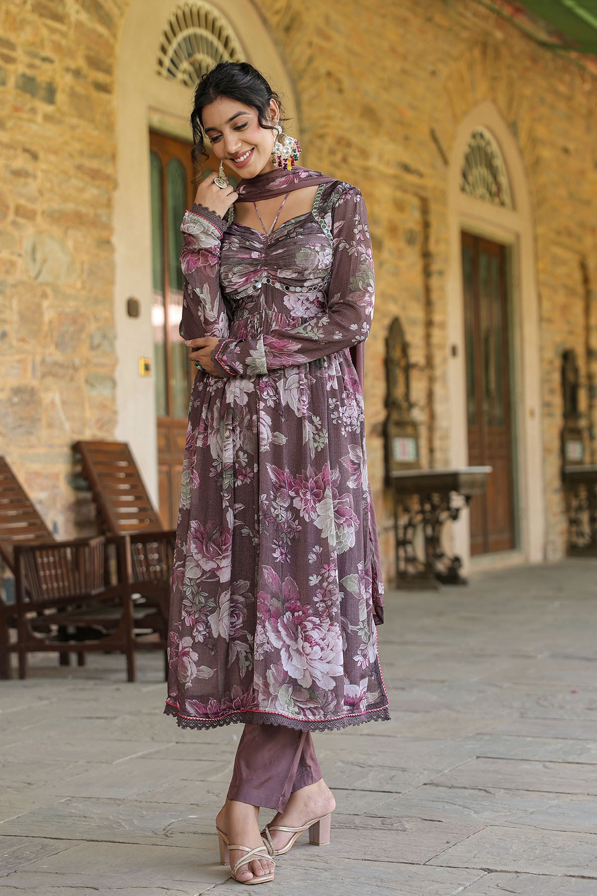 Woman in a floral dress standing in front of a stone building.