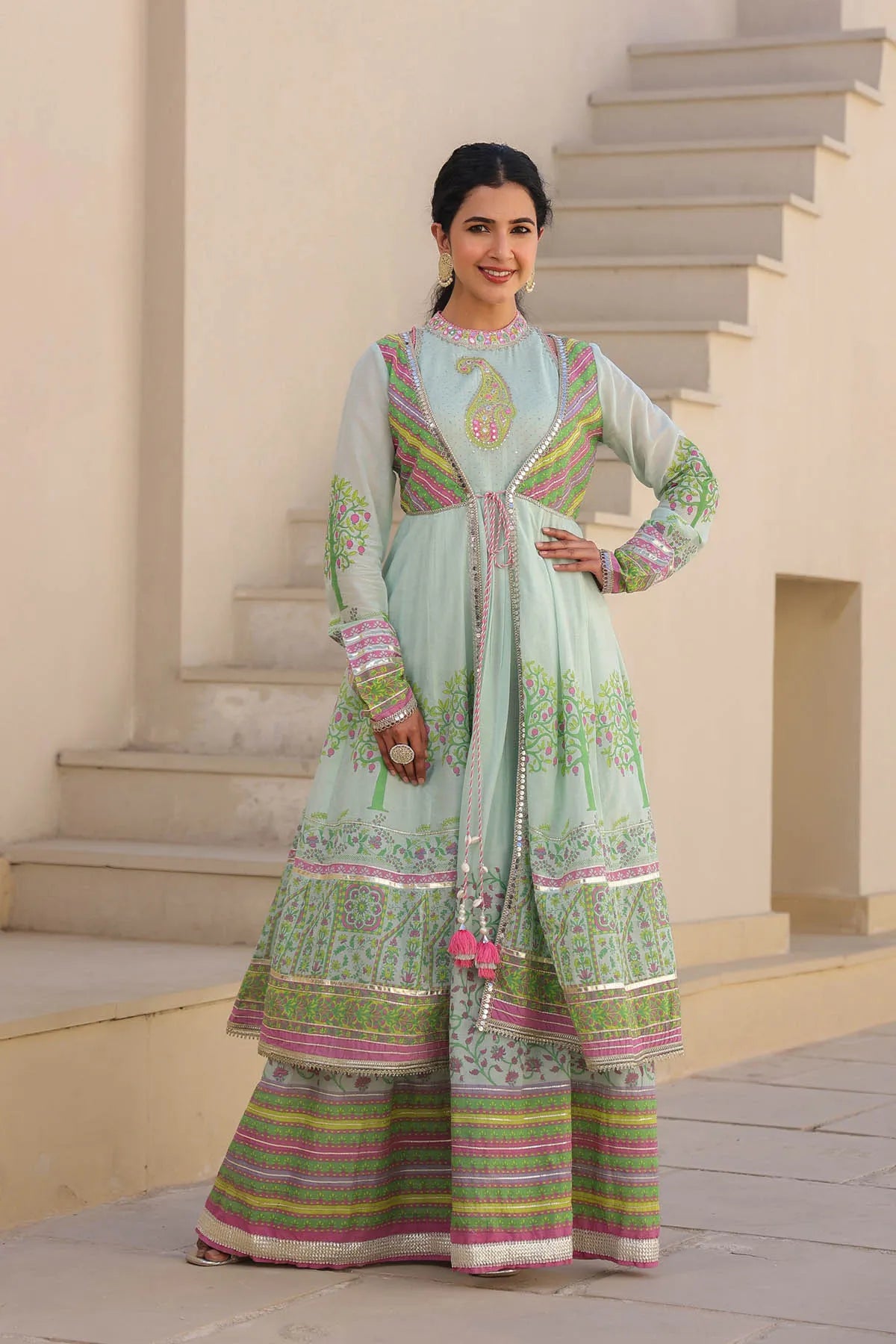 Woman wearing a traditional outfit with intricate patterns in an outdoor setting.