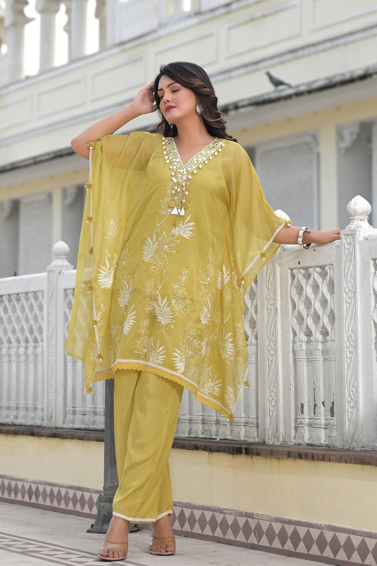 Woman in a yellow traditional outfit standing on a balcony.