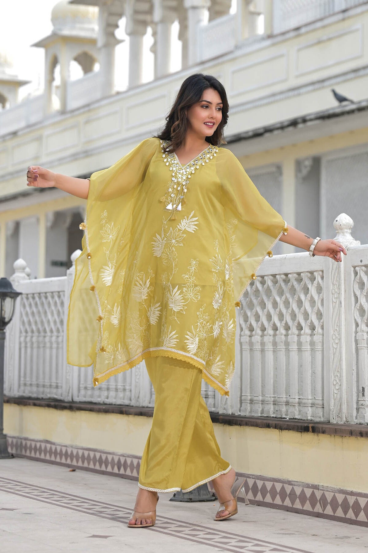 Woman in a yellow traditional outfit standing on a balcony.