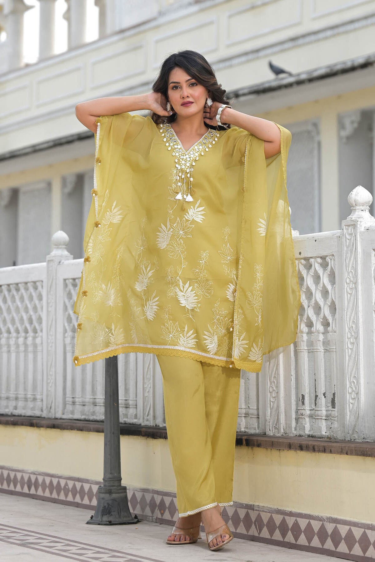 Woman in a yellow traditional outfit standing on a balcony