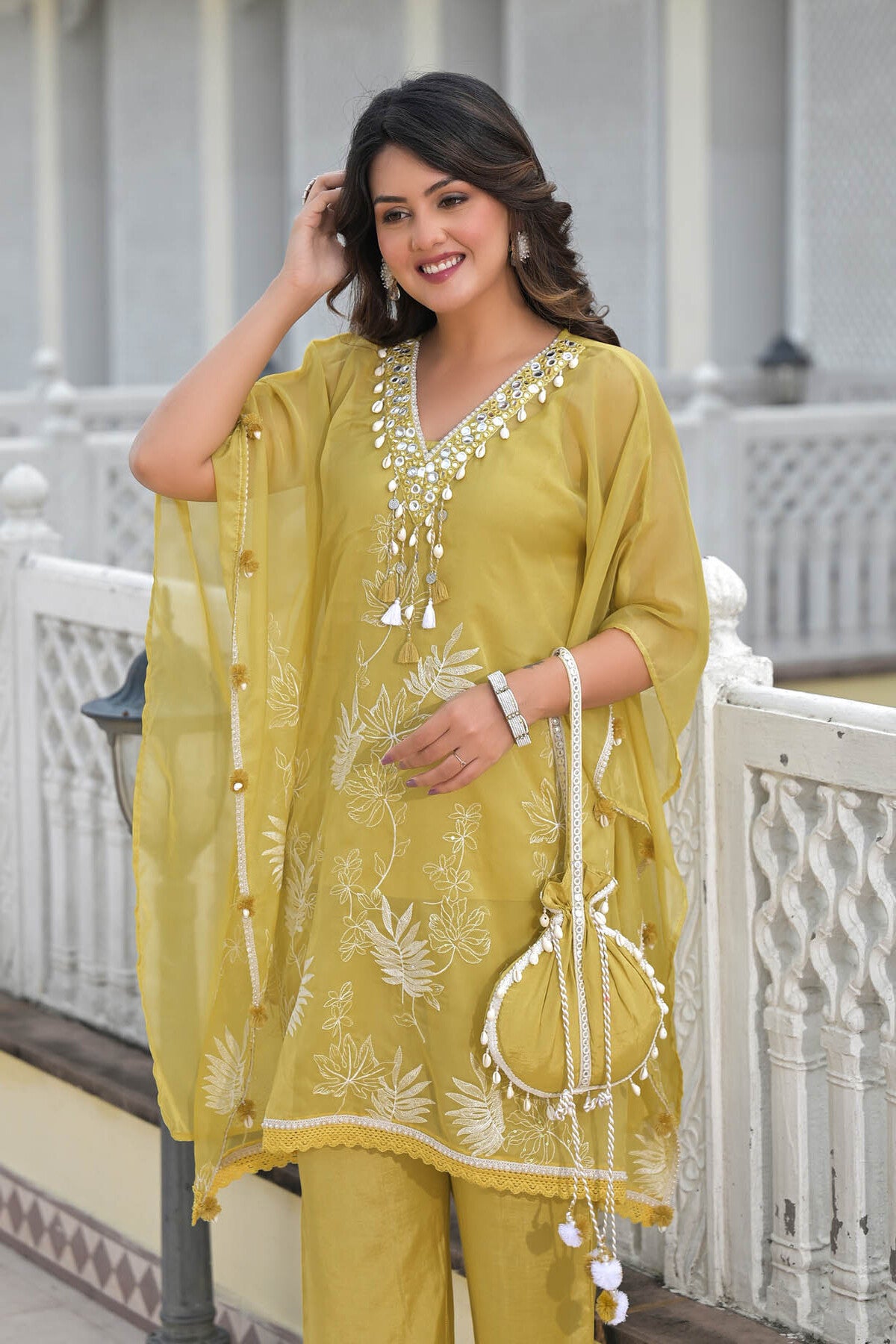 Woman wearing a yellow embroidered outfit with a white background