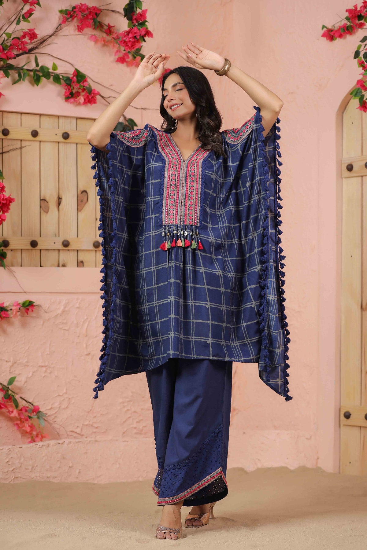 Woman wearing a blue embroidered outfit with a pink floral background