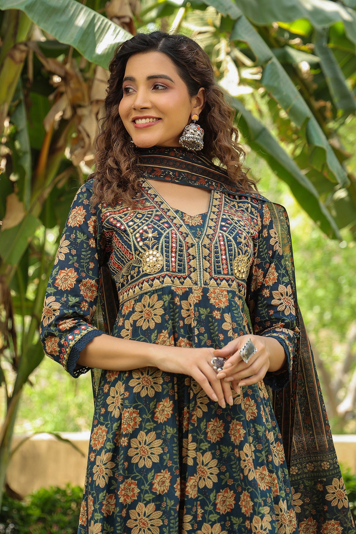 Woman wearing a floral traditional outfit with a green leafy background