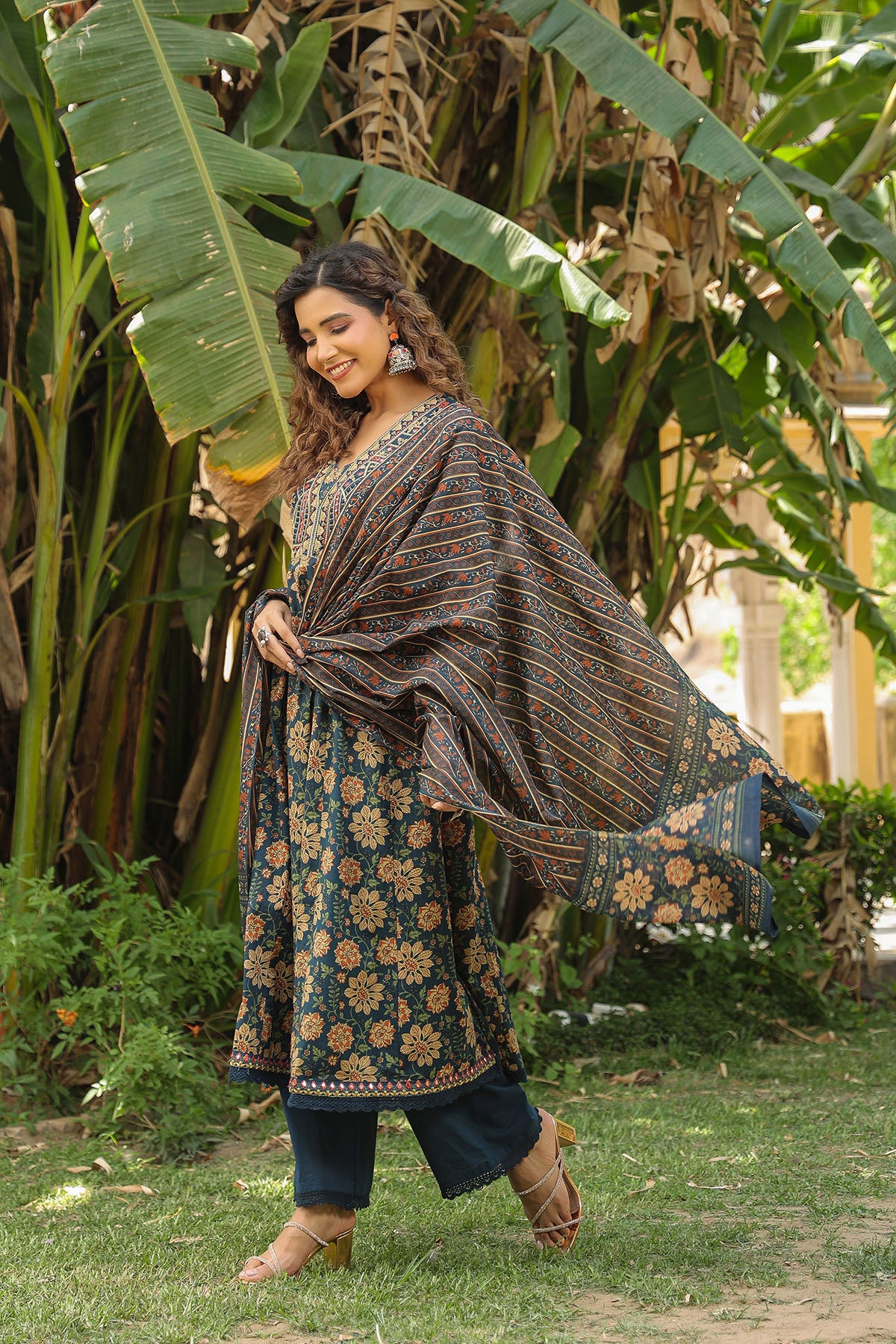 Woman in a traditional outfit standing in a lush green outdoor setting