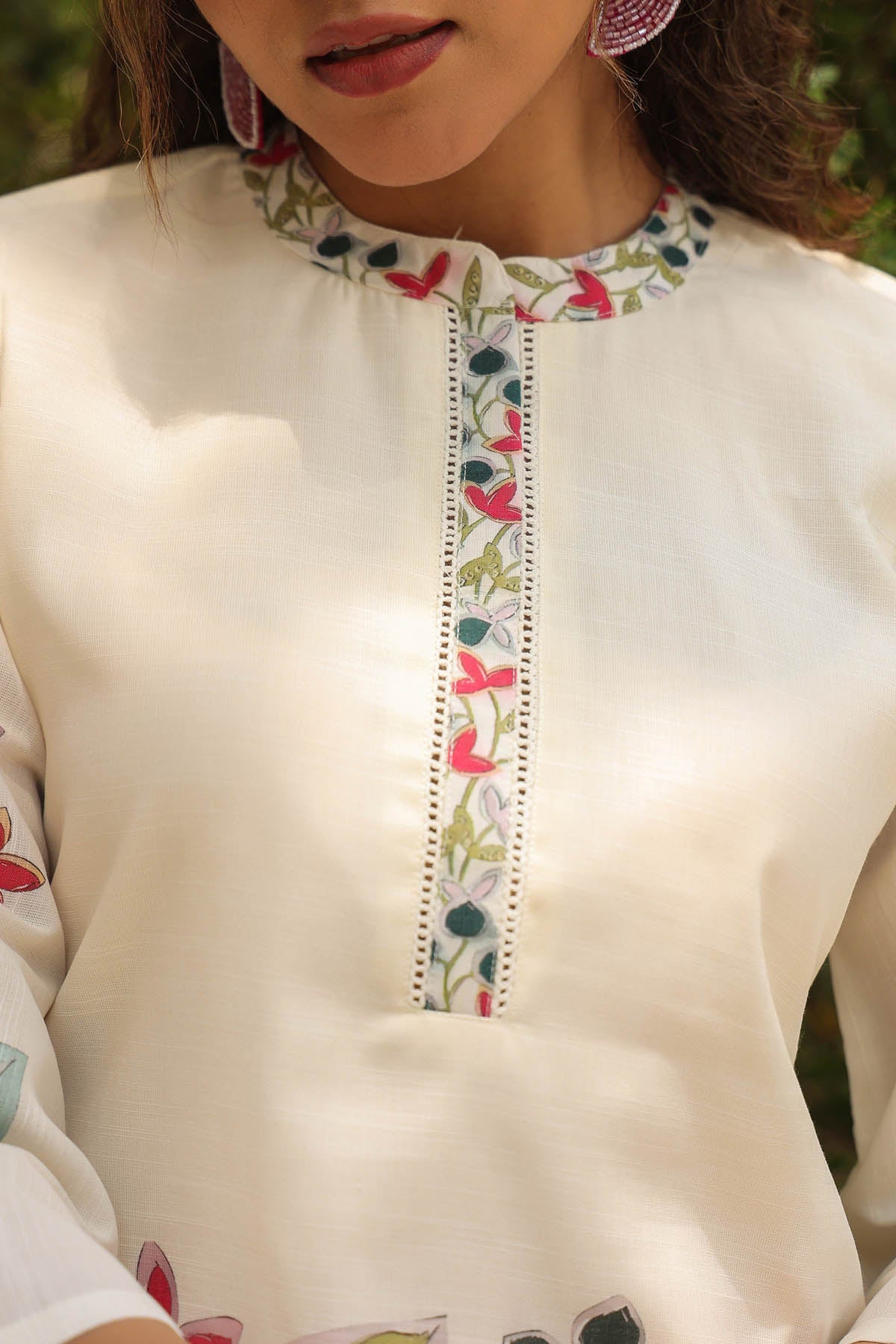 Close-up of a cream-colored top with floral embroidery on the neckline.
