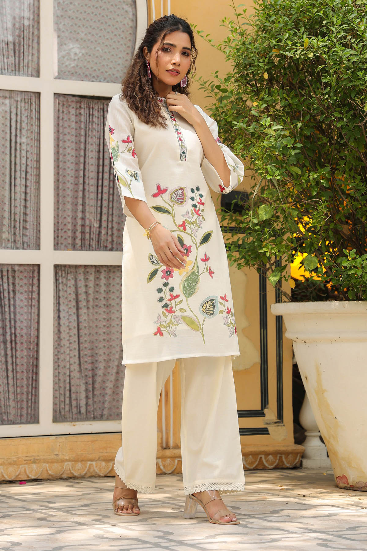 Woman wearing a white embroidered kurta with palazzo pants standing outdoors.