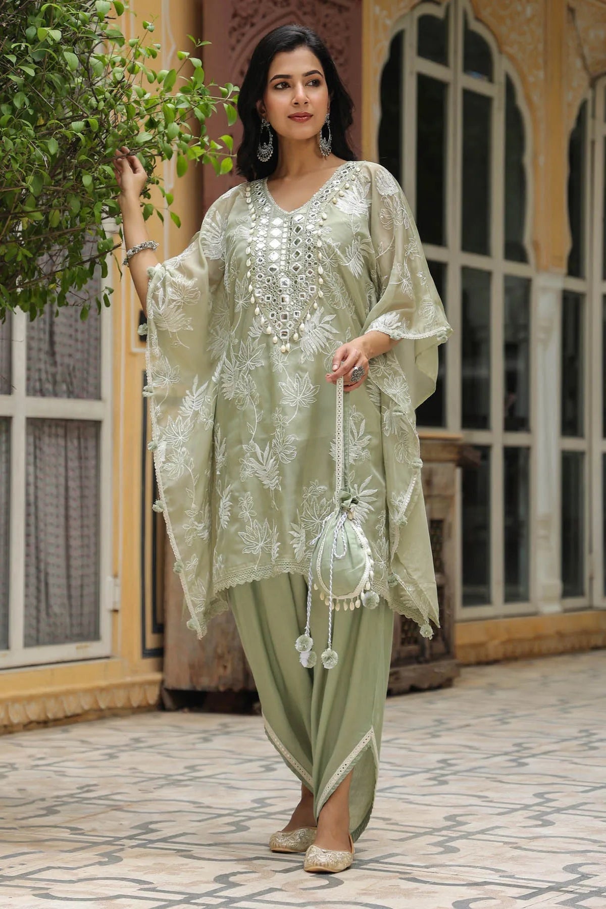 Woman wearing a light green embroidered outfit standing outdoors.