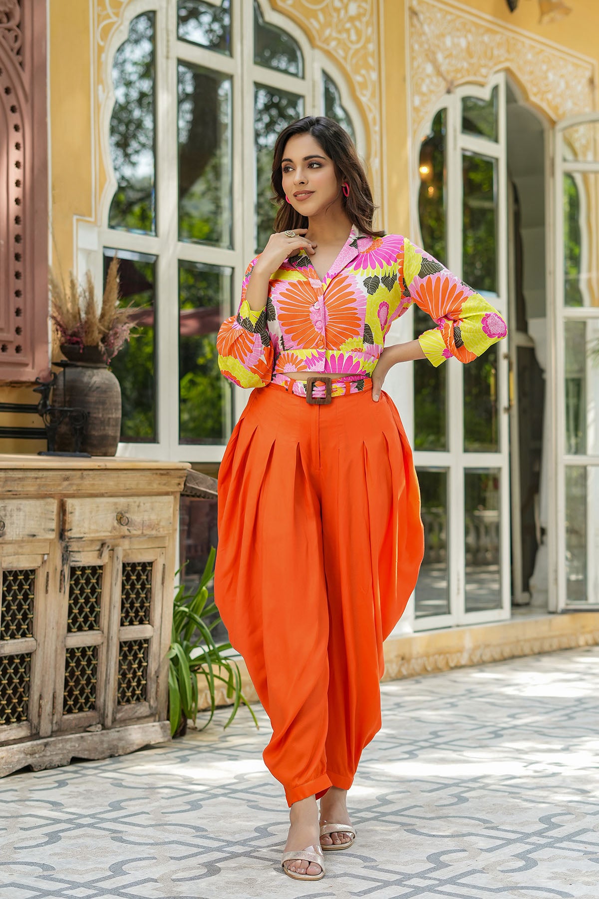 Woman in a colorful outfit standing in front of a decorative building entrance.