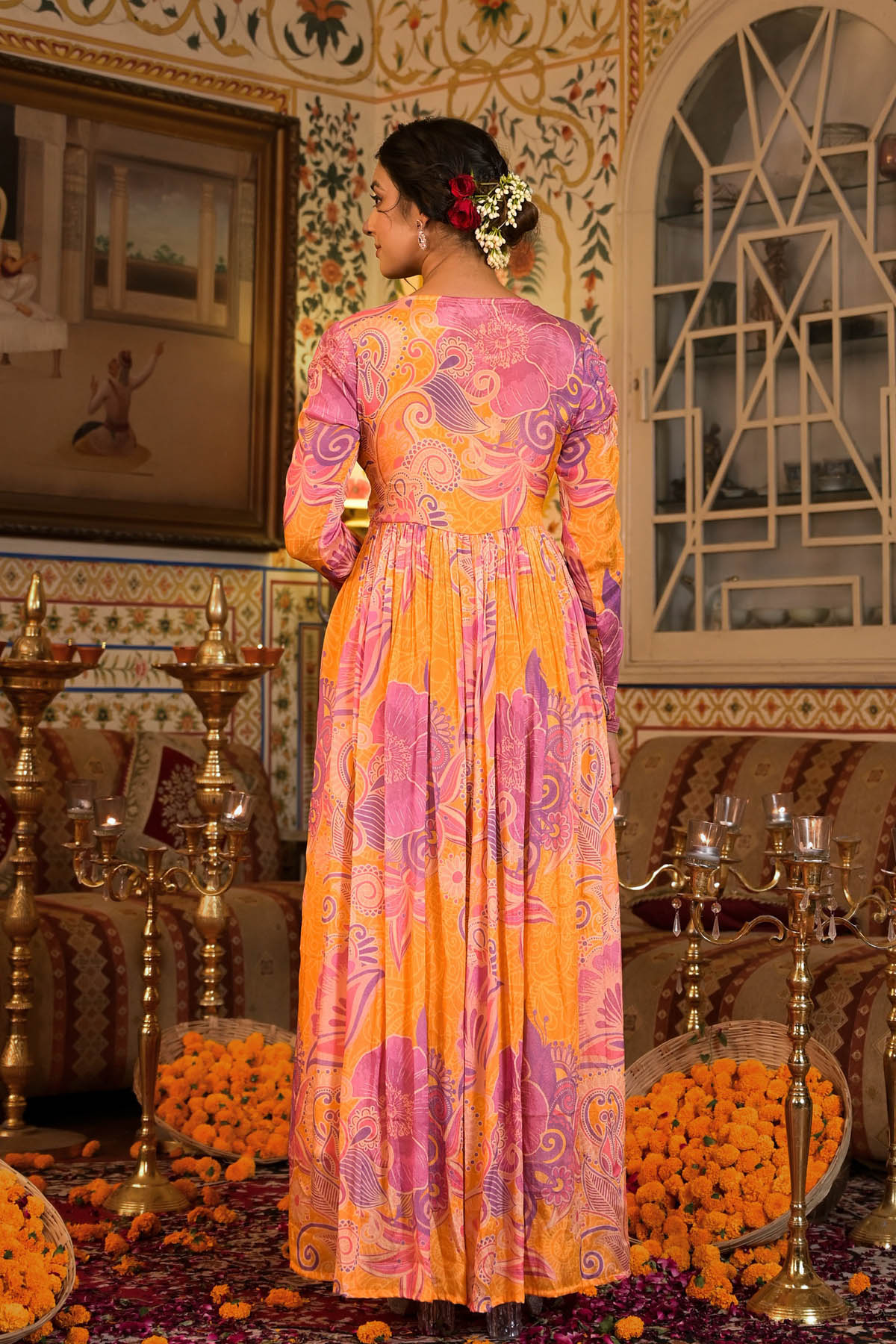 Woman in a colorful dress standing in an ornate room with decorative elements.
