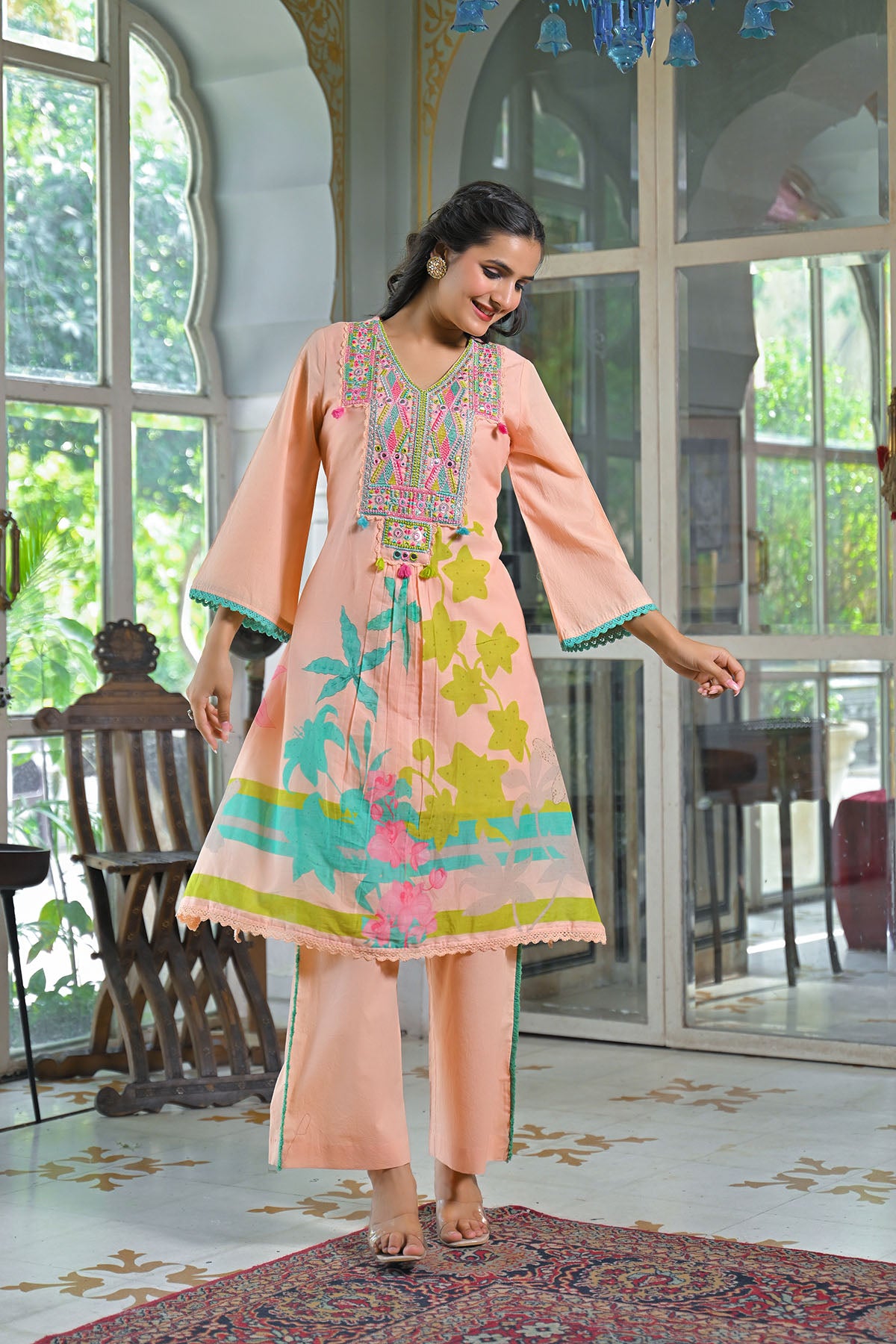 Woman in a colorful dress with floral patterns in a decorated room.