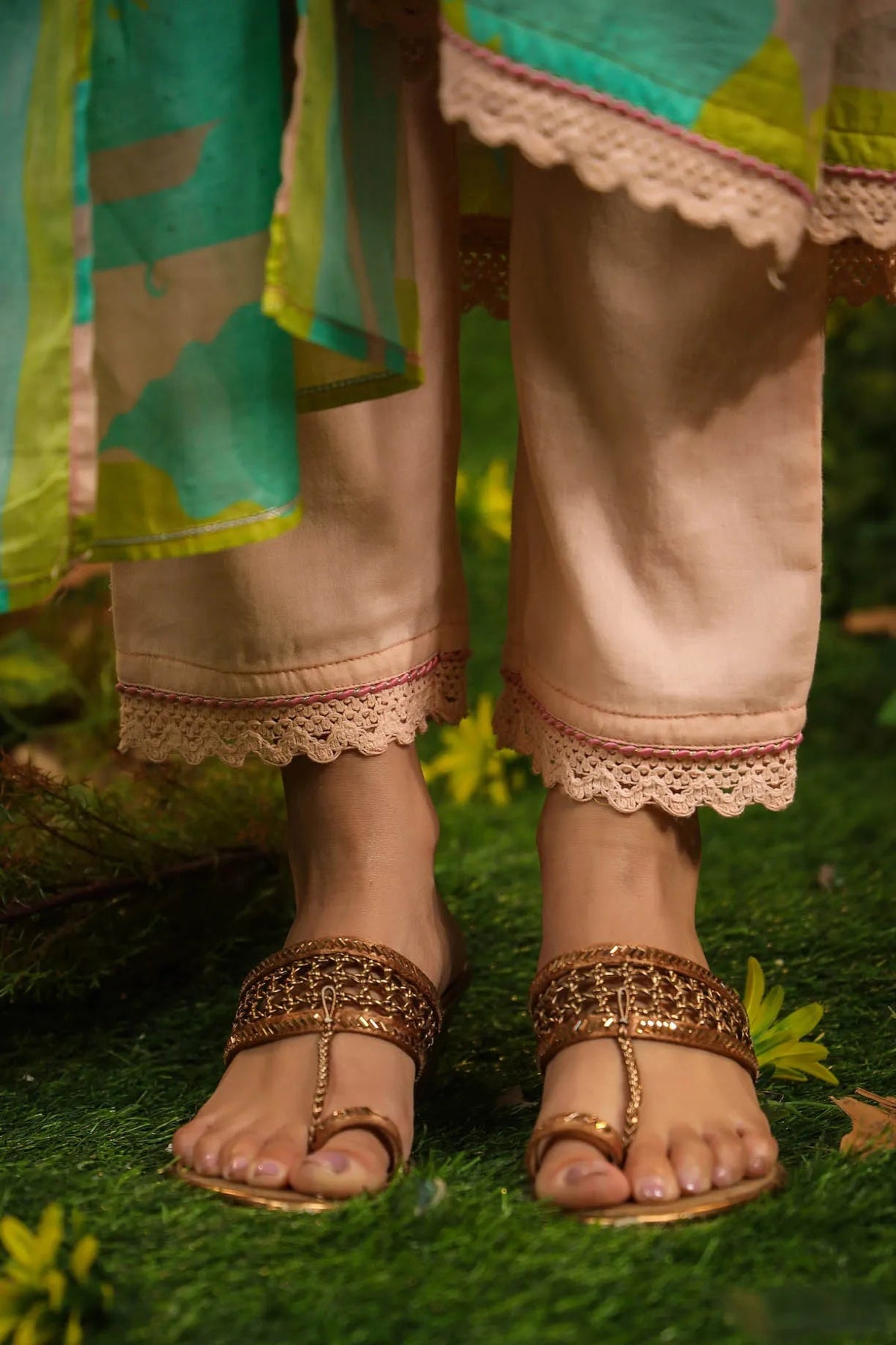 Person wearing traditional attire with gold sandals on a grassy background