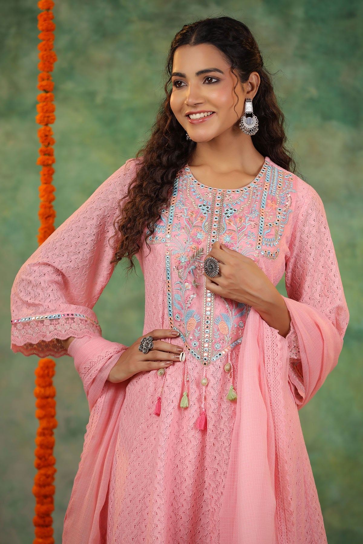 Woman wearing a pink embroidered traditional outfit with a green background
