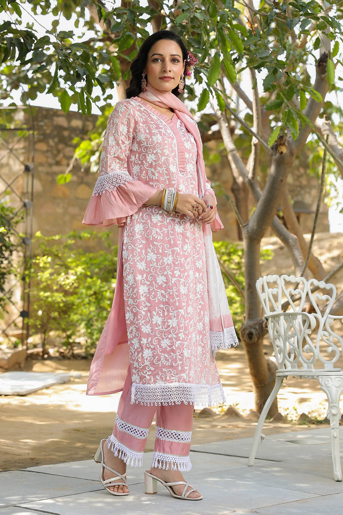 Woman in a pink traditional outfit standing outdoors with trees in the background