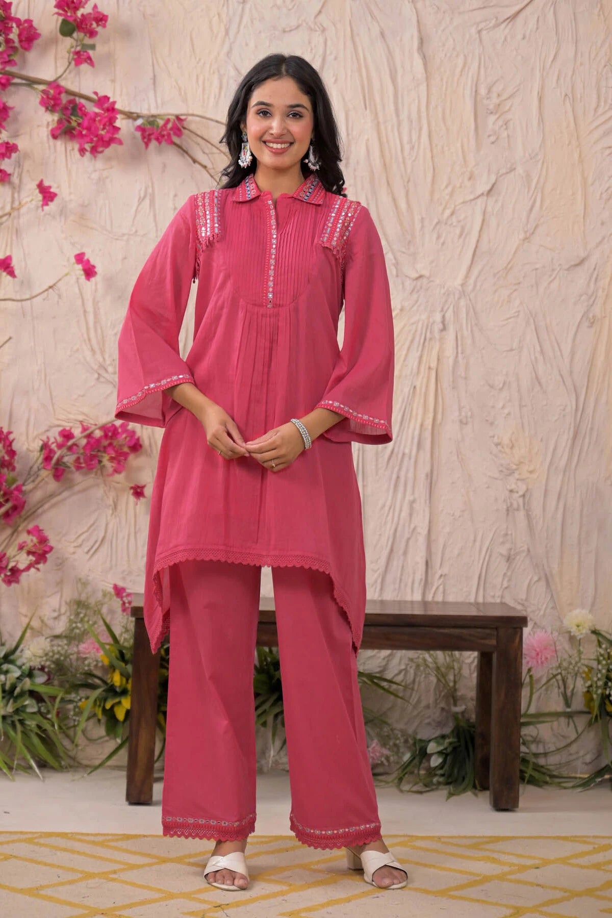 Woman wearing a pink traditional outfit with floral decorations in the background