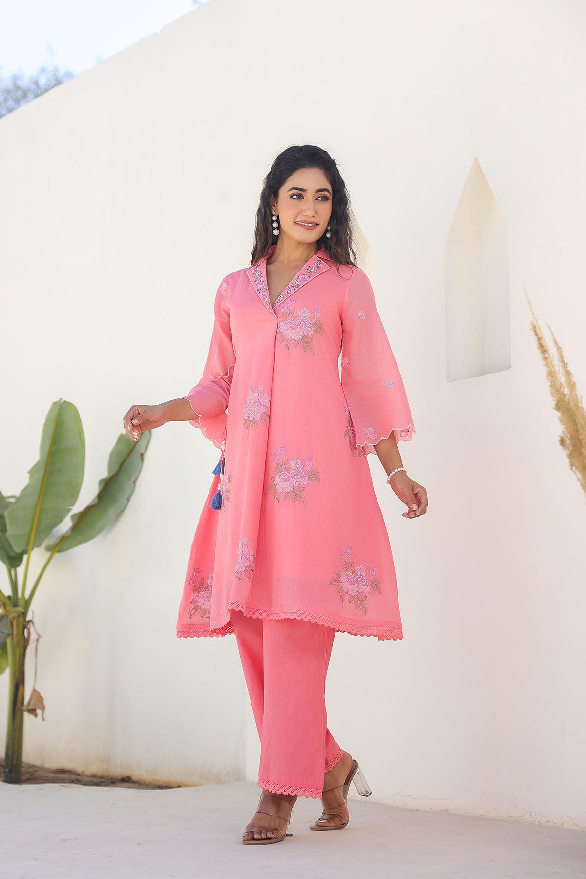 Woman wearing a pink traditional outfit with floral patterns against a white background