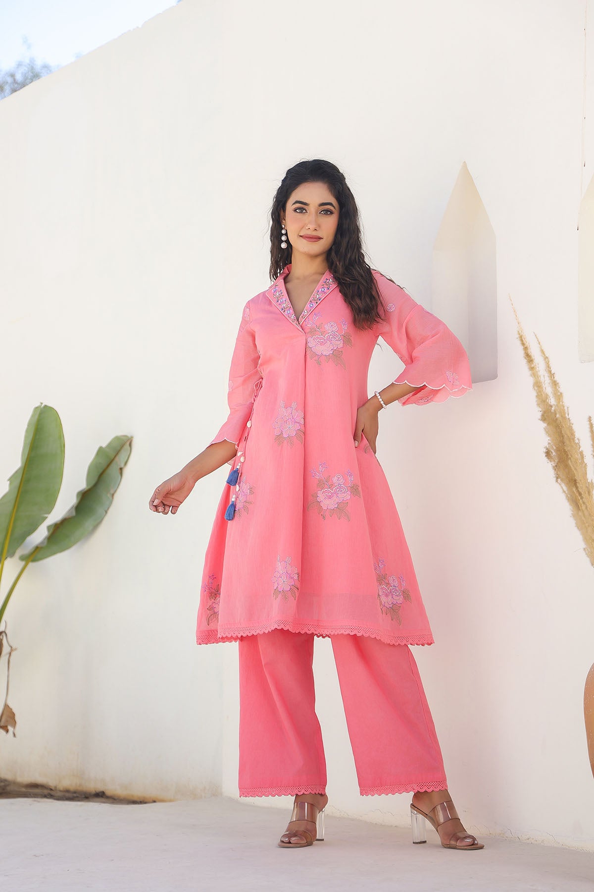 Woman wearing a pink traditional outfit with floral patterns against a white background