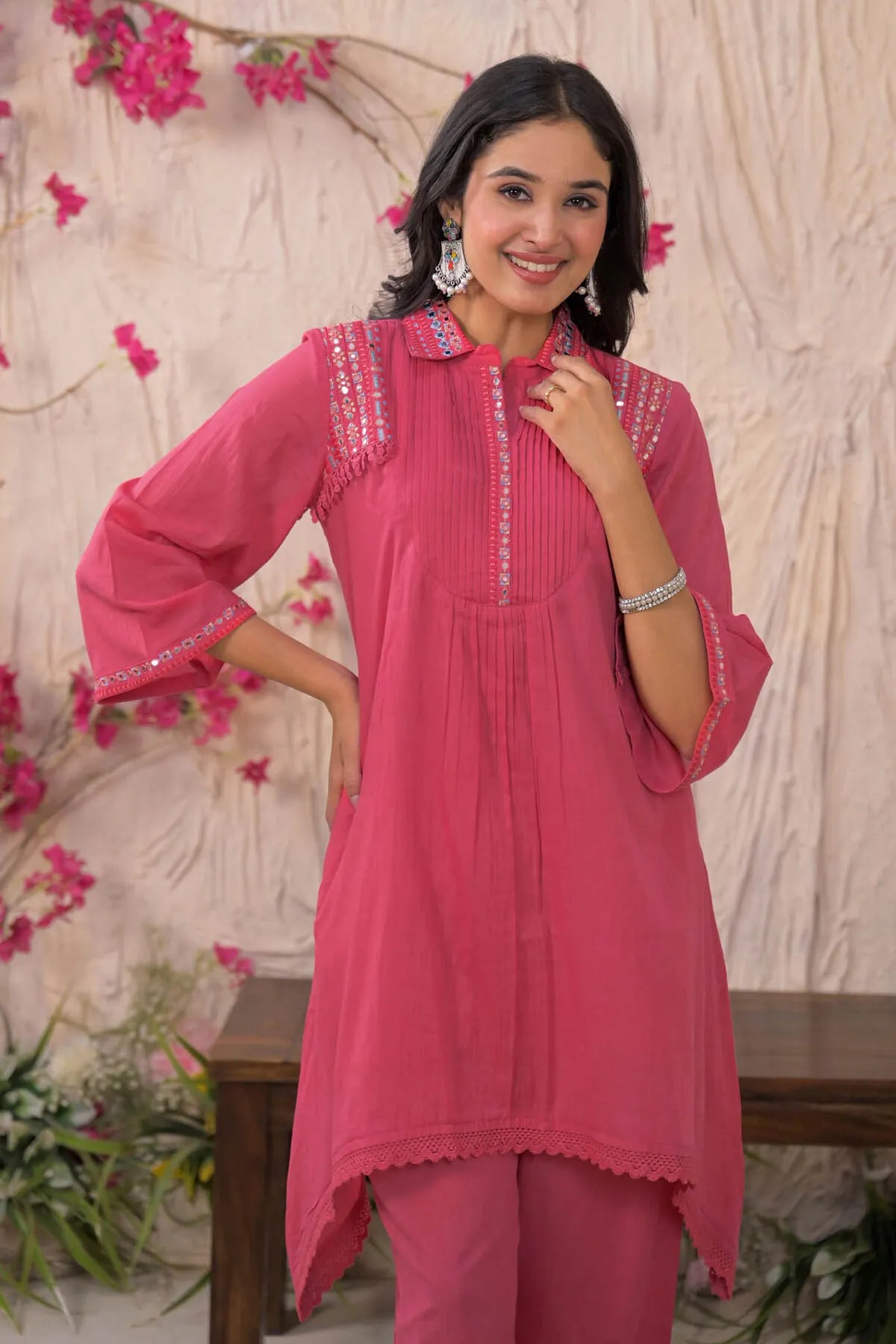 Woman wearing a pink traditional outfit with floral decorations in the background