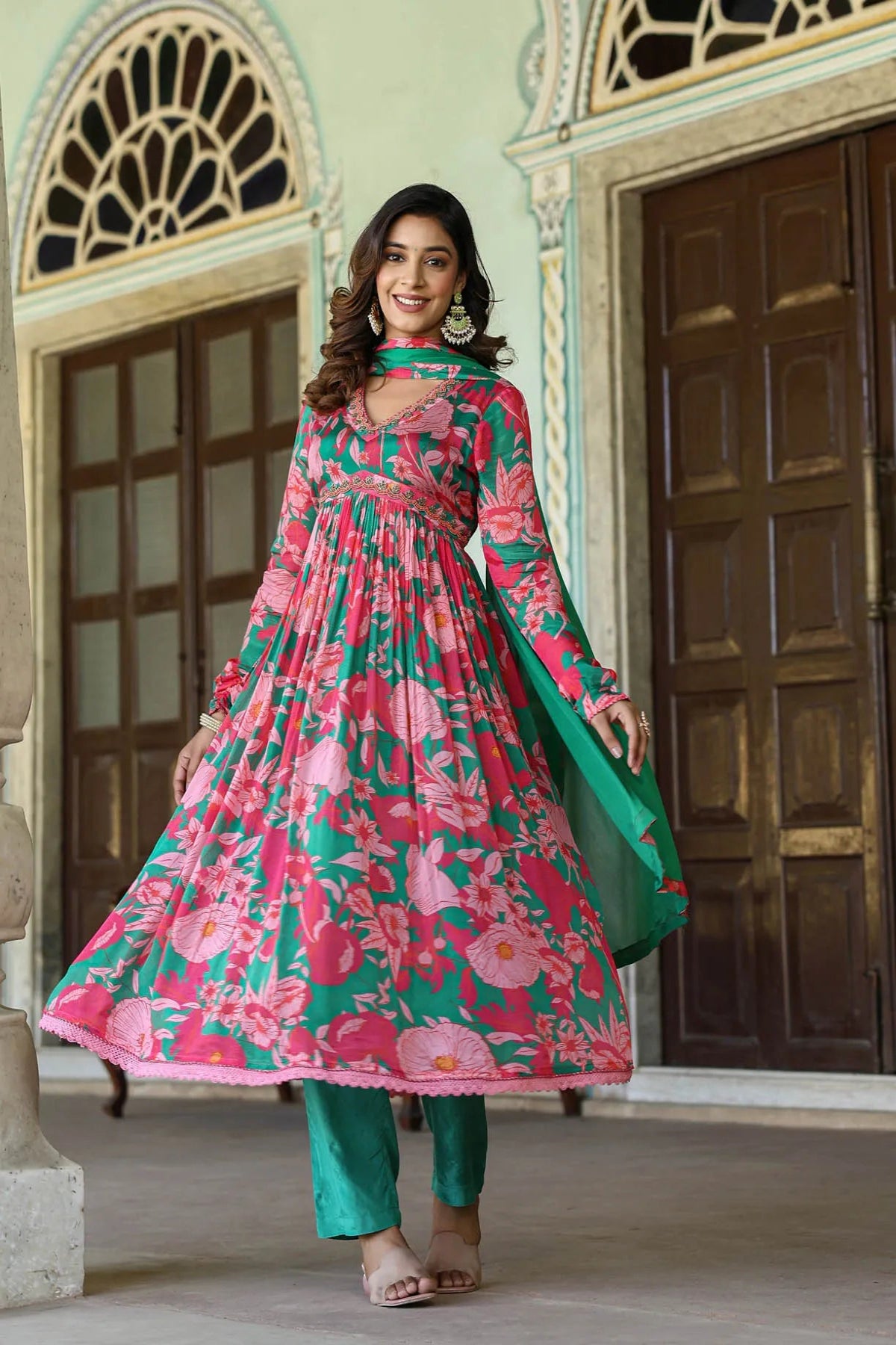 Woman in a floral dress standing in front of an ornate building entrance.