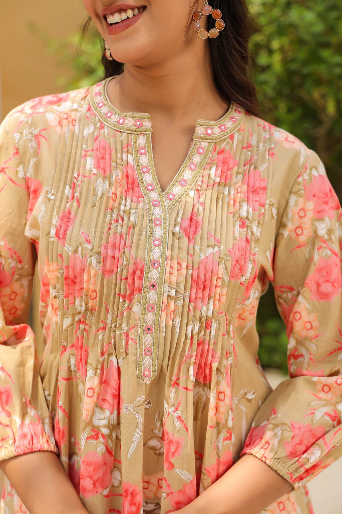 Woman wearing a floral patterned top with a blurred green background