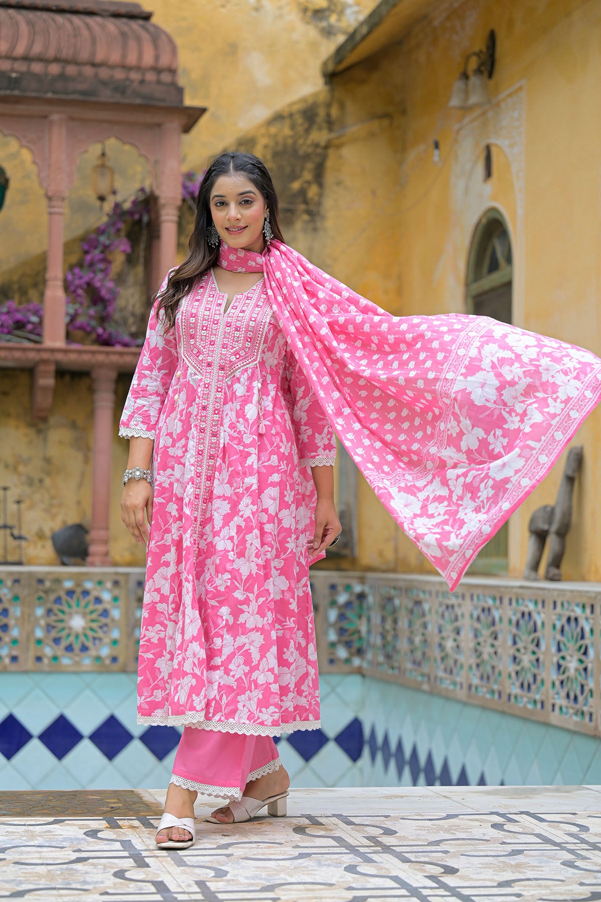 Woman in a pink traditional outfit standing in front of a decorative building.