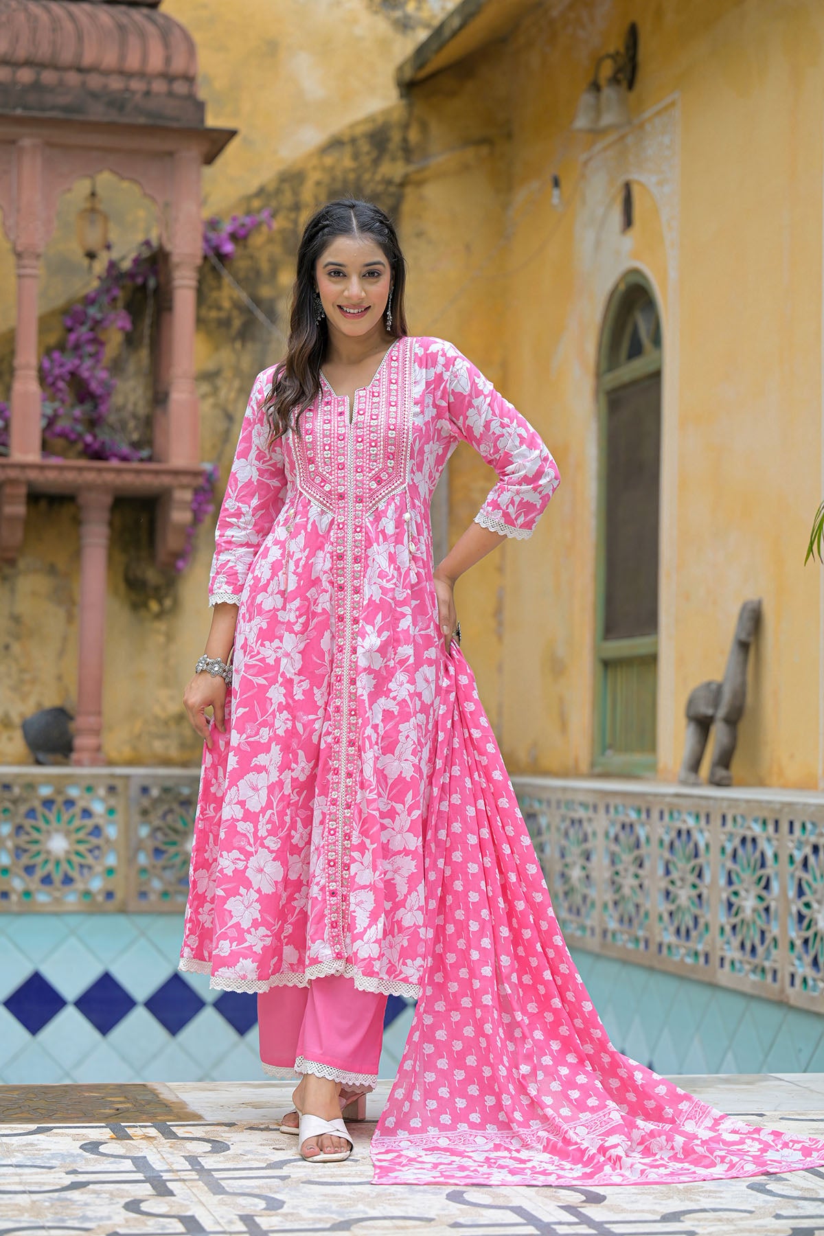 Woman in a pink traditional outfit standing in front of a decorative building.