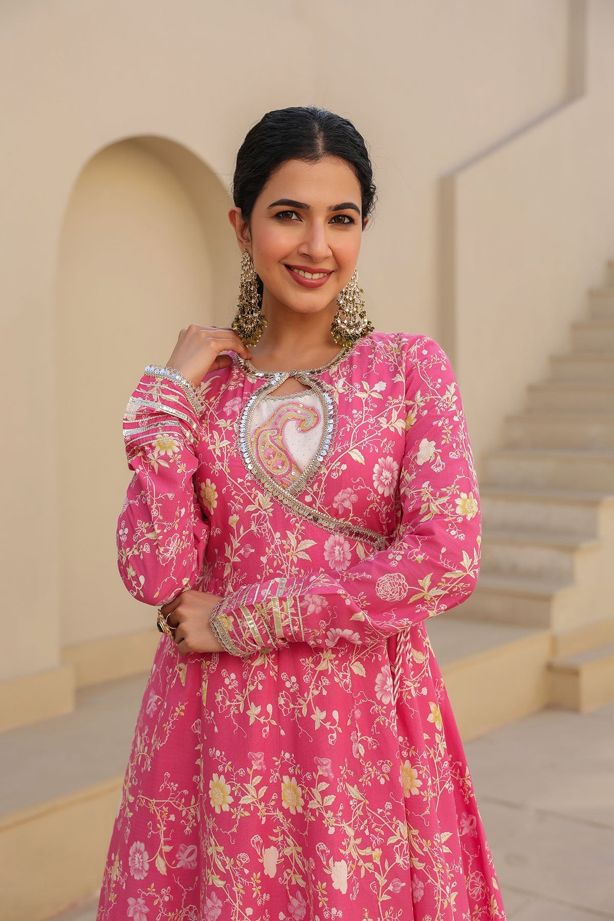 Woman in a pink floral dress standing in an elegant interior setting