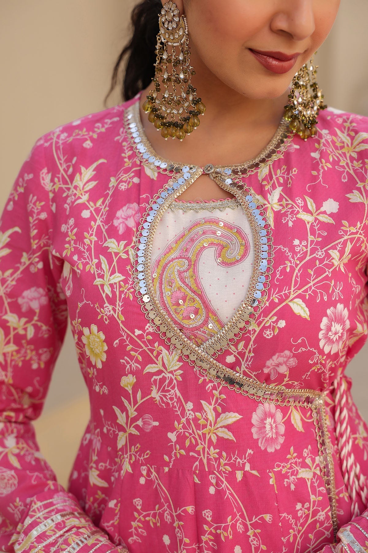 Person wearing a pink traditional outfit with intricate embroidery and jewelry.