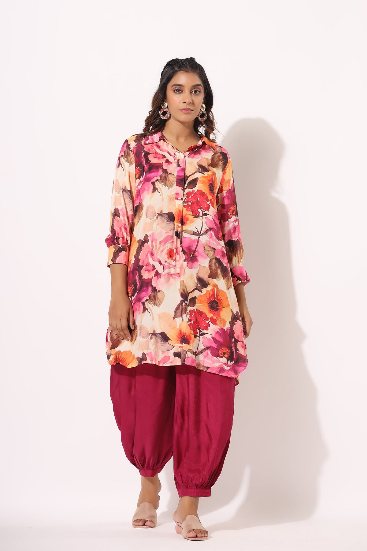 Woman wearing a floral top and pink pants on a white background