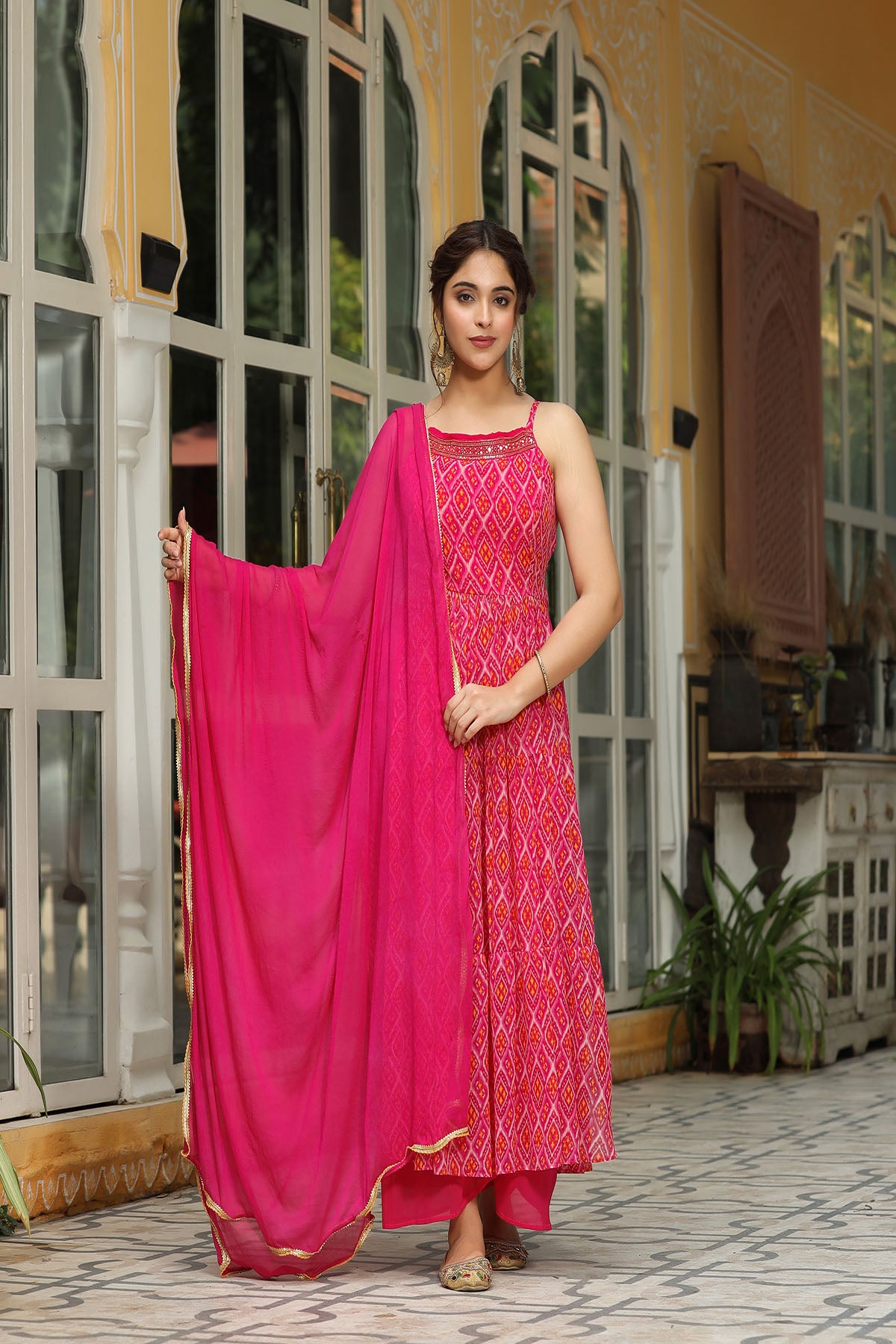 Woman wearing a pink traditional outfit with a matching dupatta in an outdoor setting.
