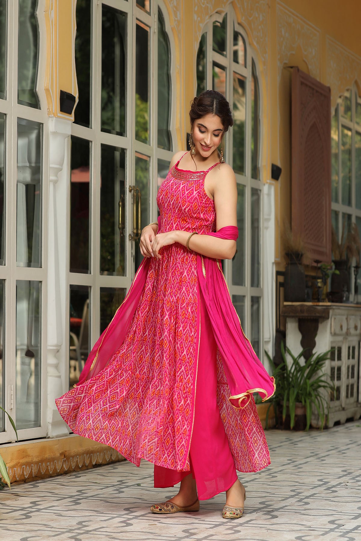 Woman in a pink traditional outfit standing in front of a glass door.
