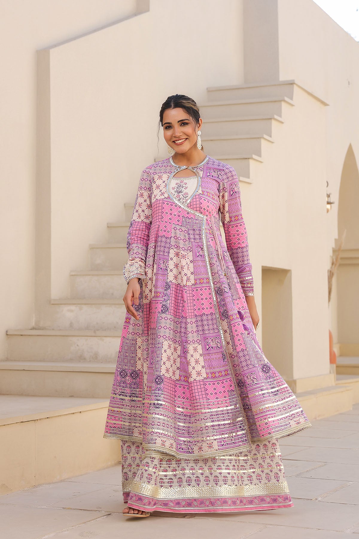 Woman in a pink and white patterned dress standing outdoors.