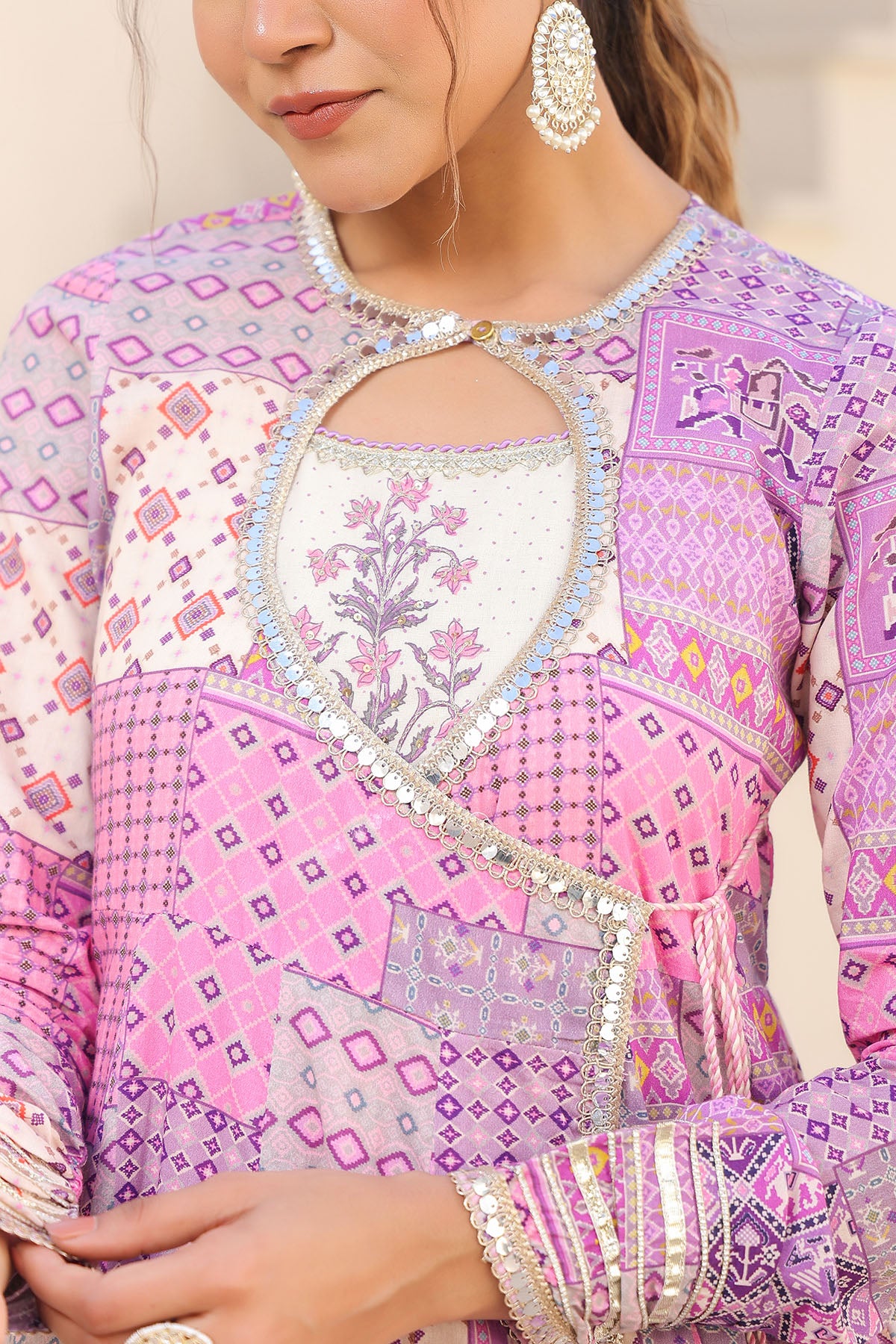 Close-up of a person wearing a pink and purple embroidered traditional outfit.