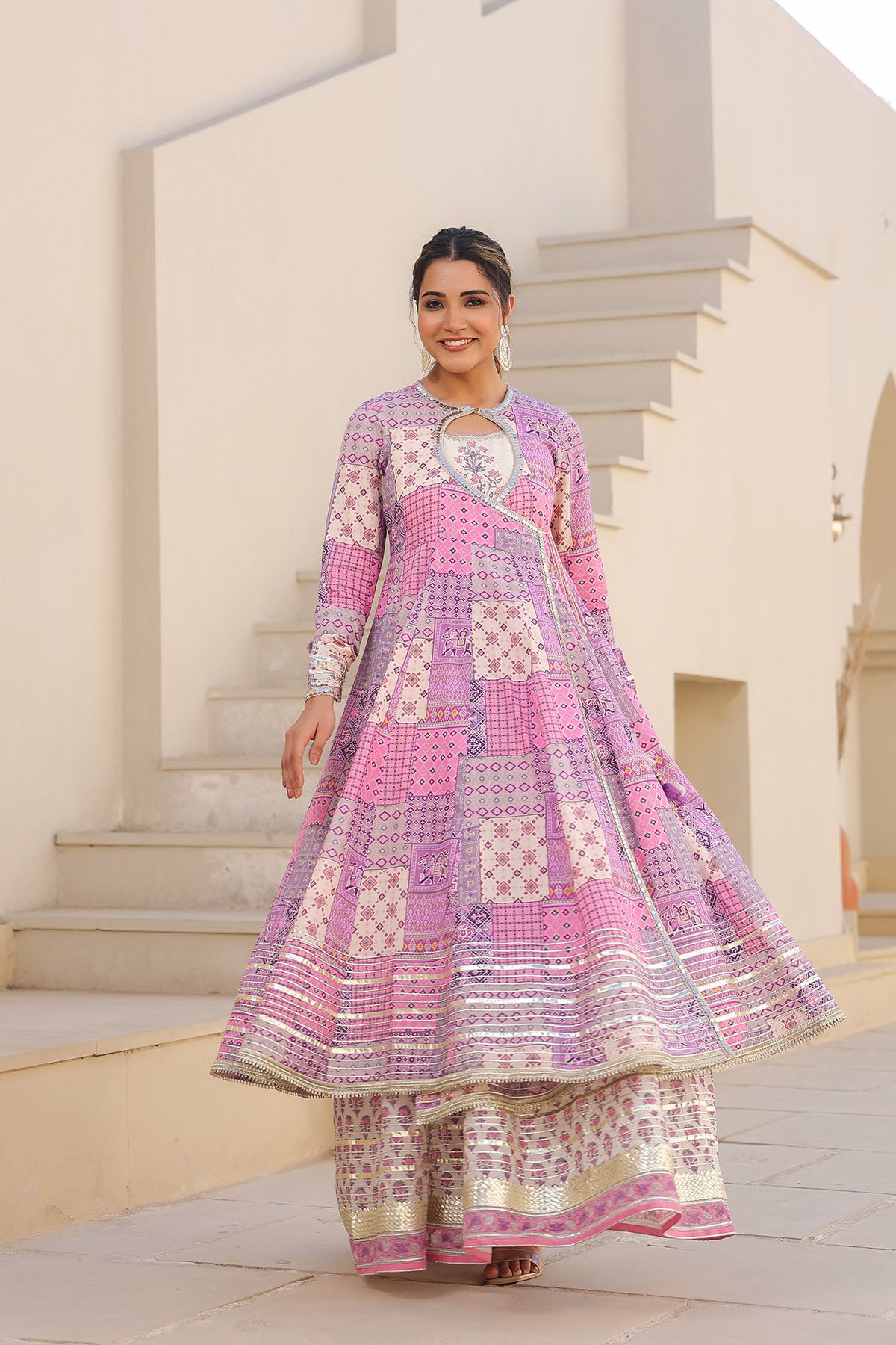 Woman wearing a pink and white patterned traditional outfit standing outdoors.