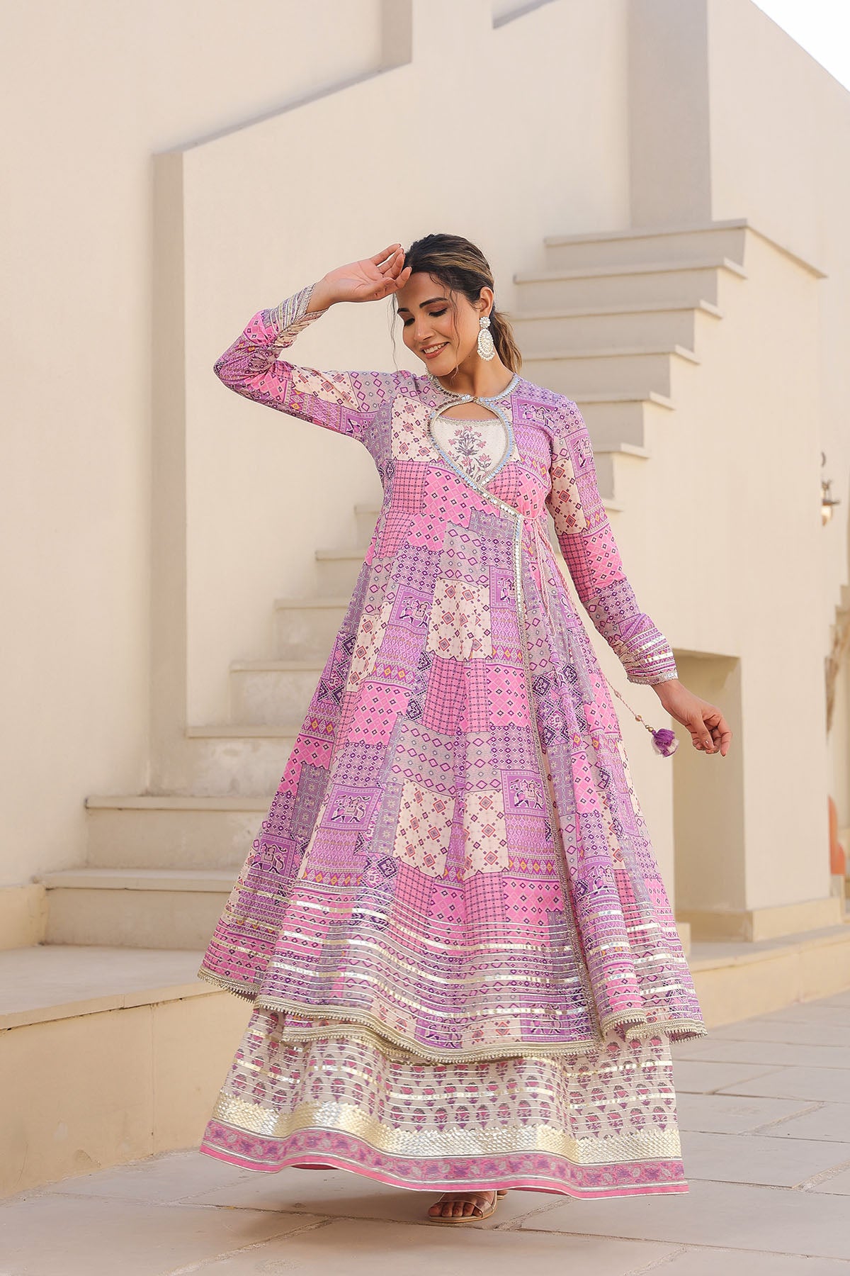 Woman wearing a pink and white patterned traditional outfit standing outdoors.