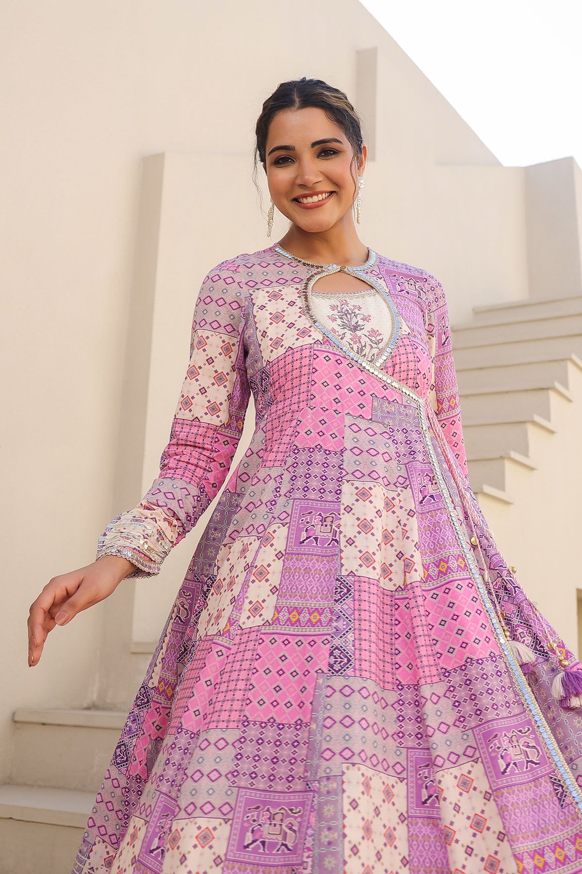 Woman wearing a pink and purple patterned dress standing outdoors.