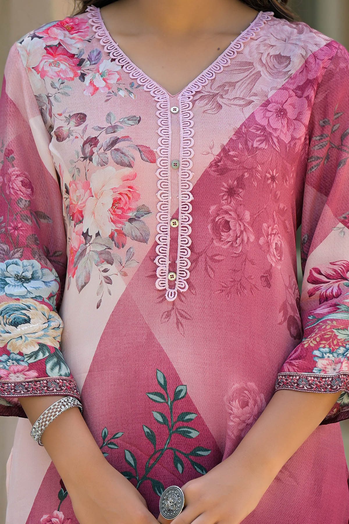 Floral embroidered pink and red traditional outfit with a blurred background