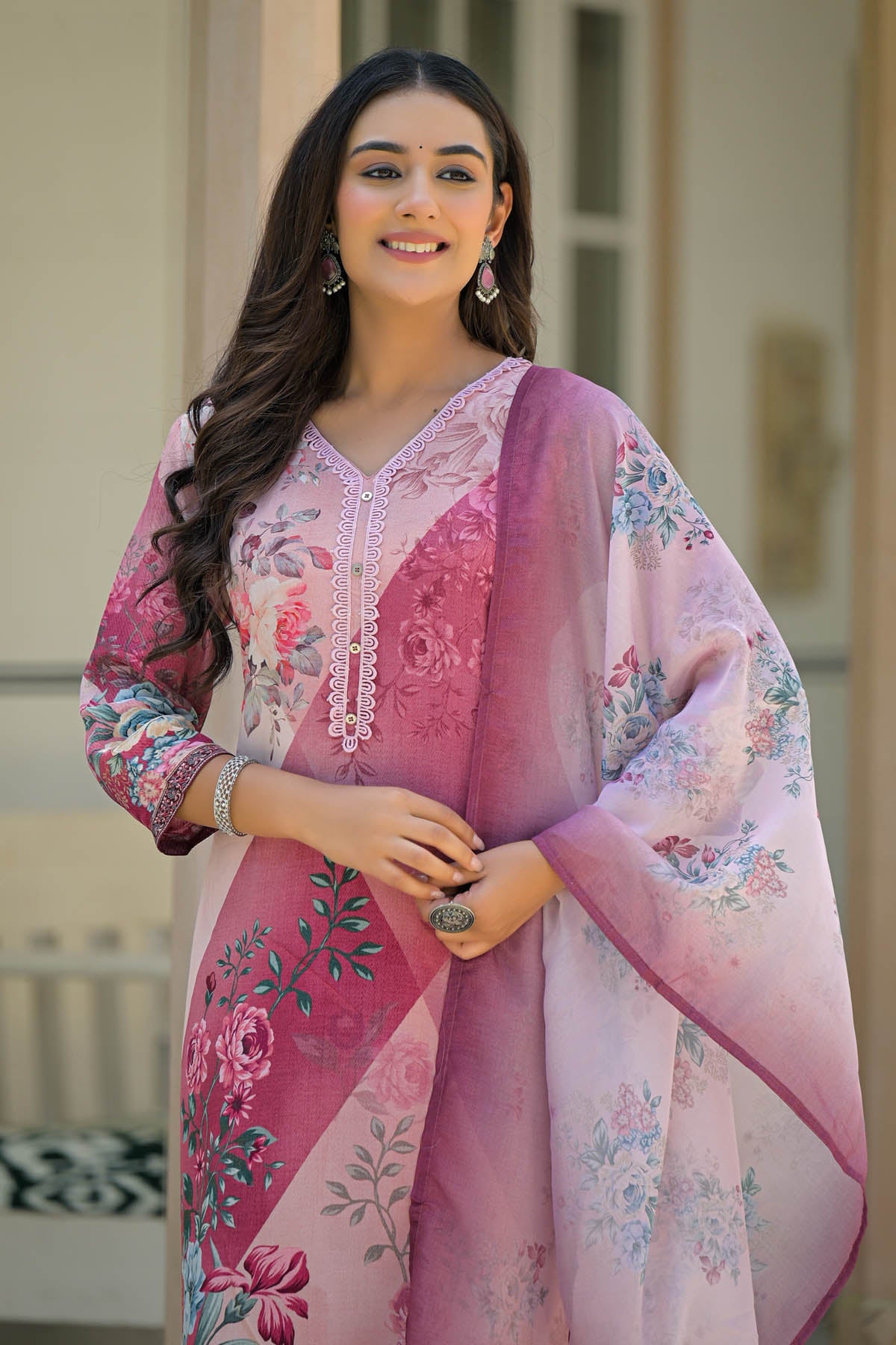 Woman wearing a pink and white embroidered traditional outfit with a floral design.