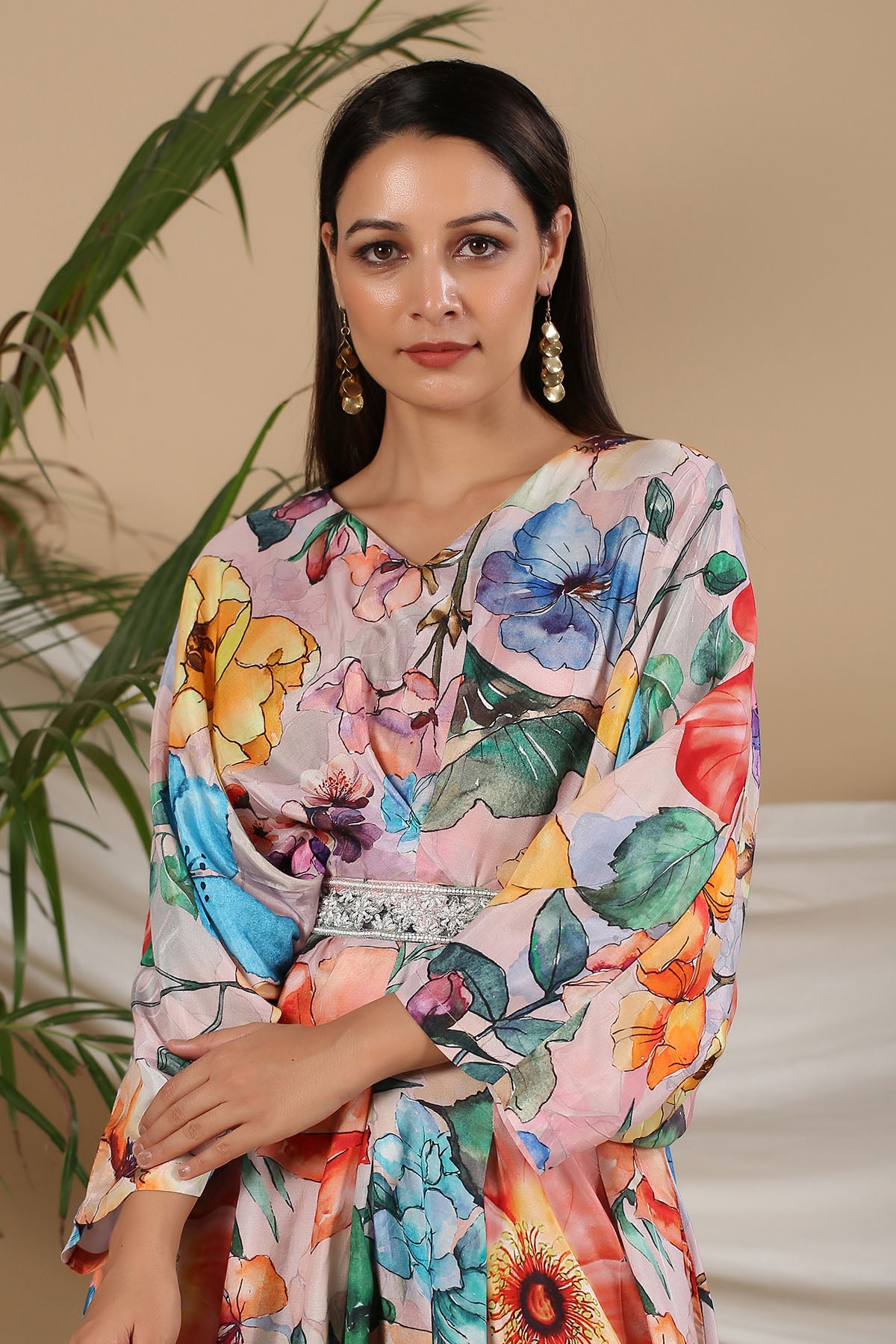 Woman wearing a colorful floral dress with a plant in the background