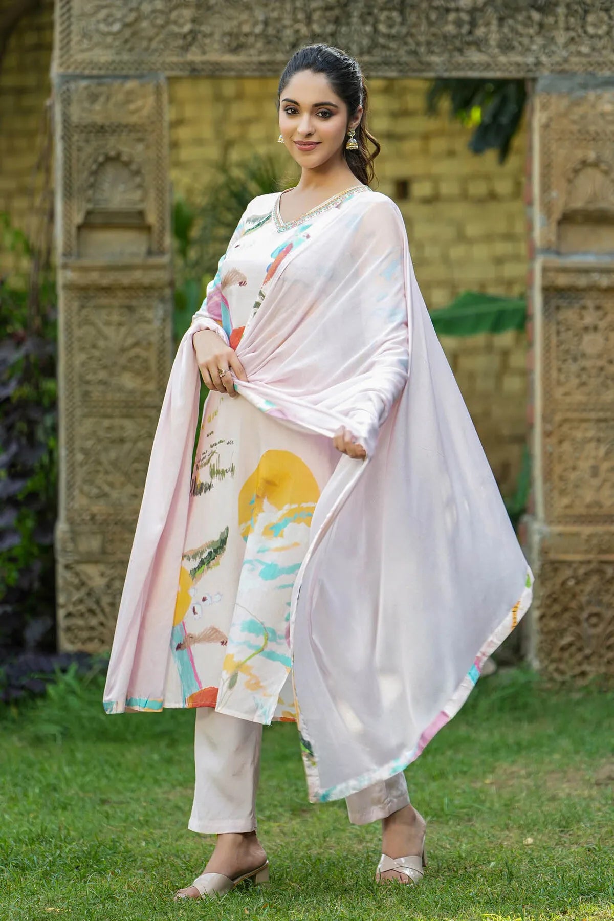 Woman in a traditional outfit with a floral design standing outdoors.