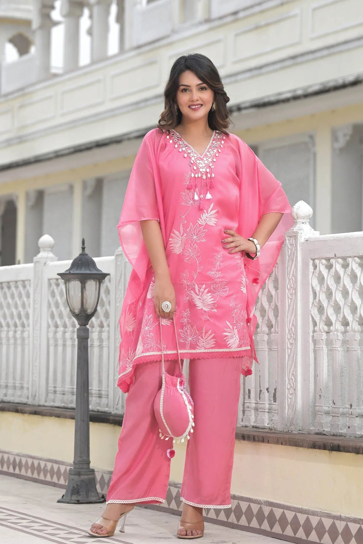Woman in a pink traditional outfit standing in front of a white building.