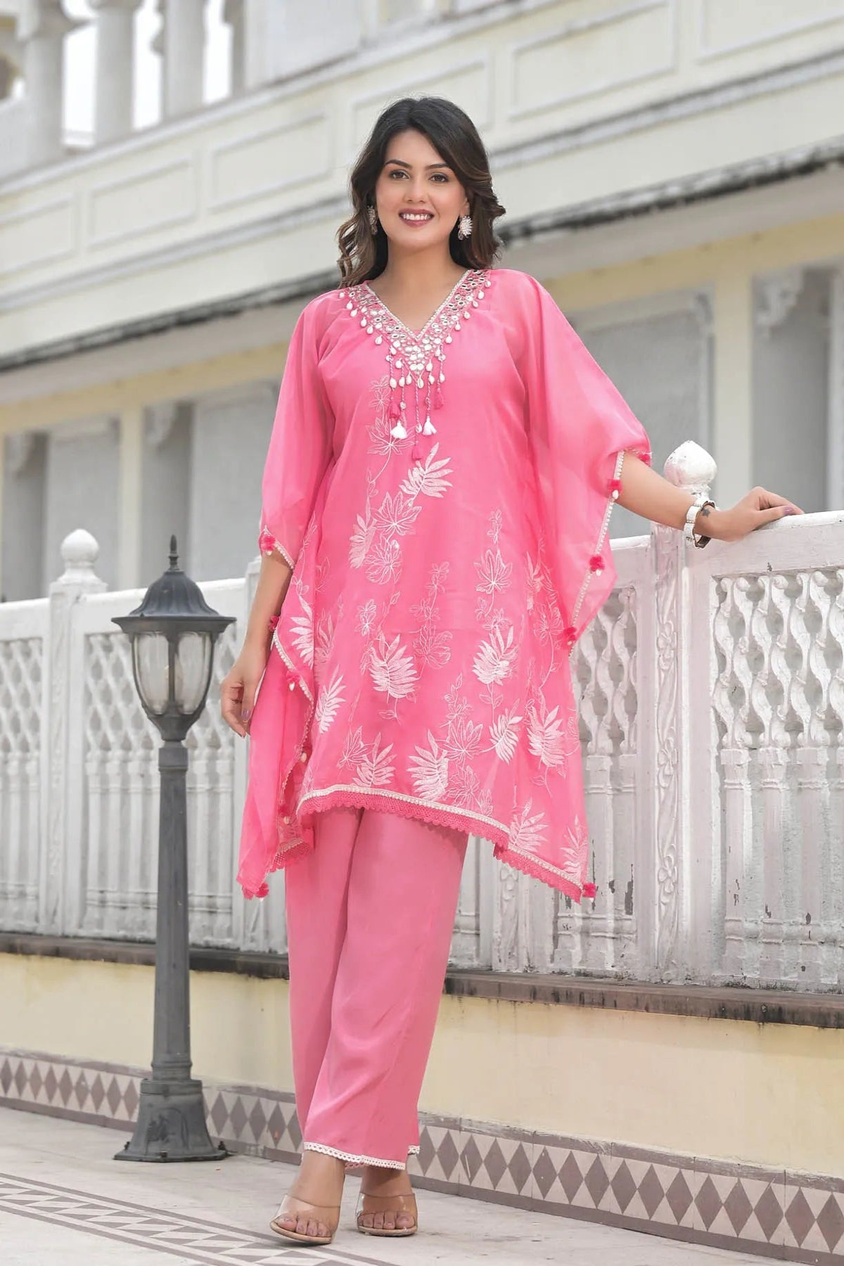 Woman in a pink traditional outfit standing on a balcony.